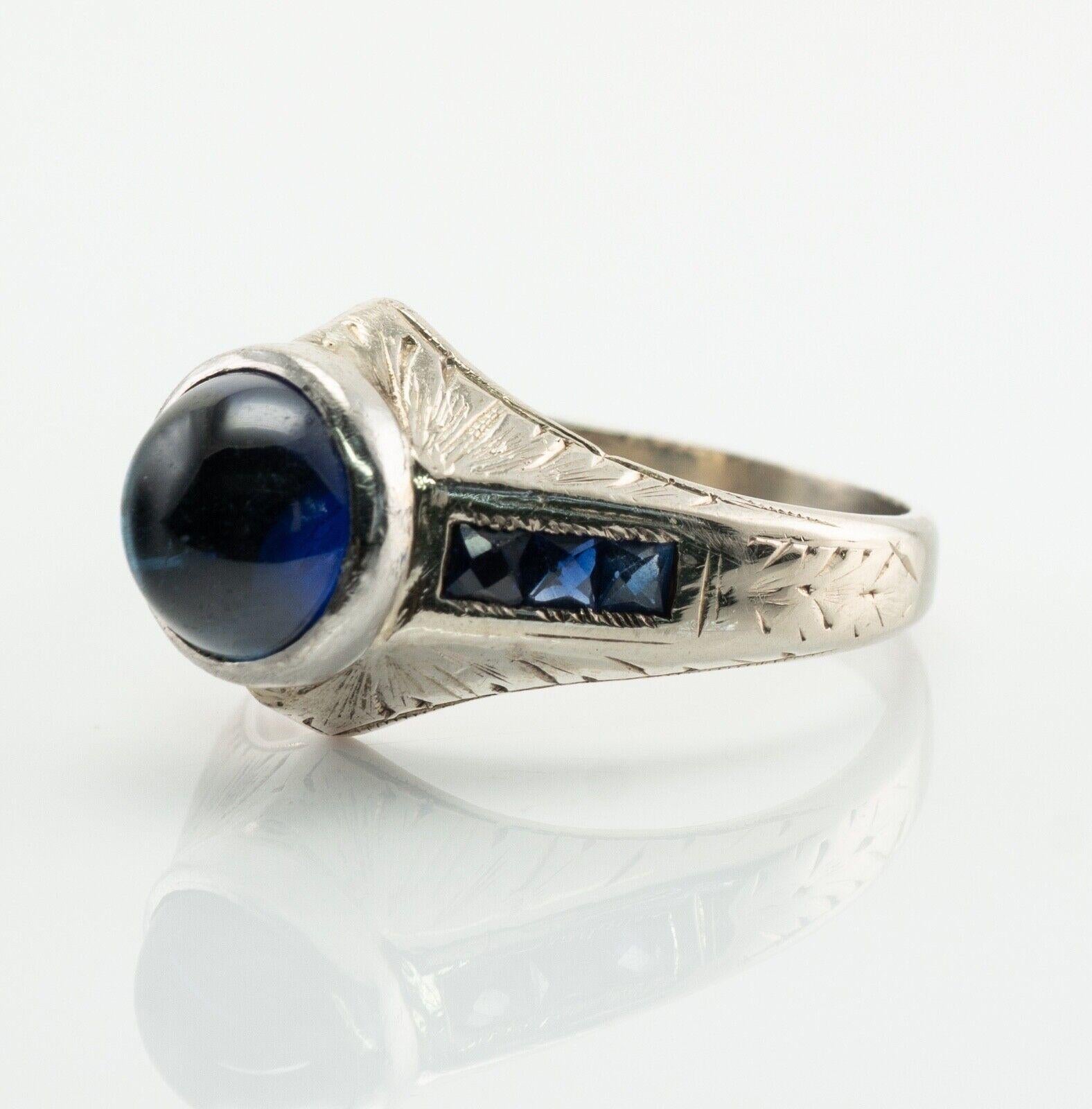 This vintage circa 1930s ring is crafted in solid 14K White gold. The center Sapphire cabochon measures 8mm. The stone looks like a good quality synthetic gem. Six french cut side sapphires are 2mm each. All gemstones are original to the setting and