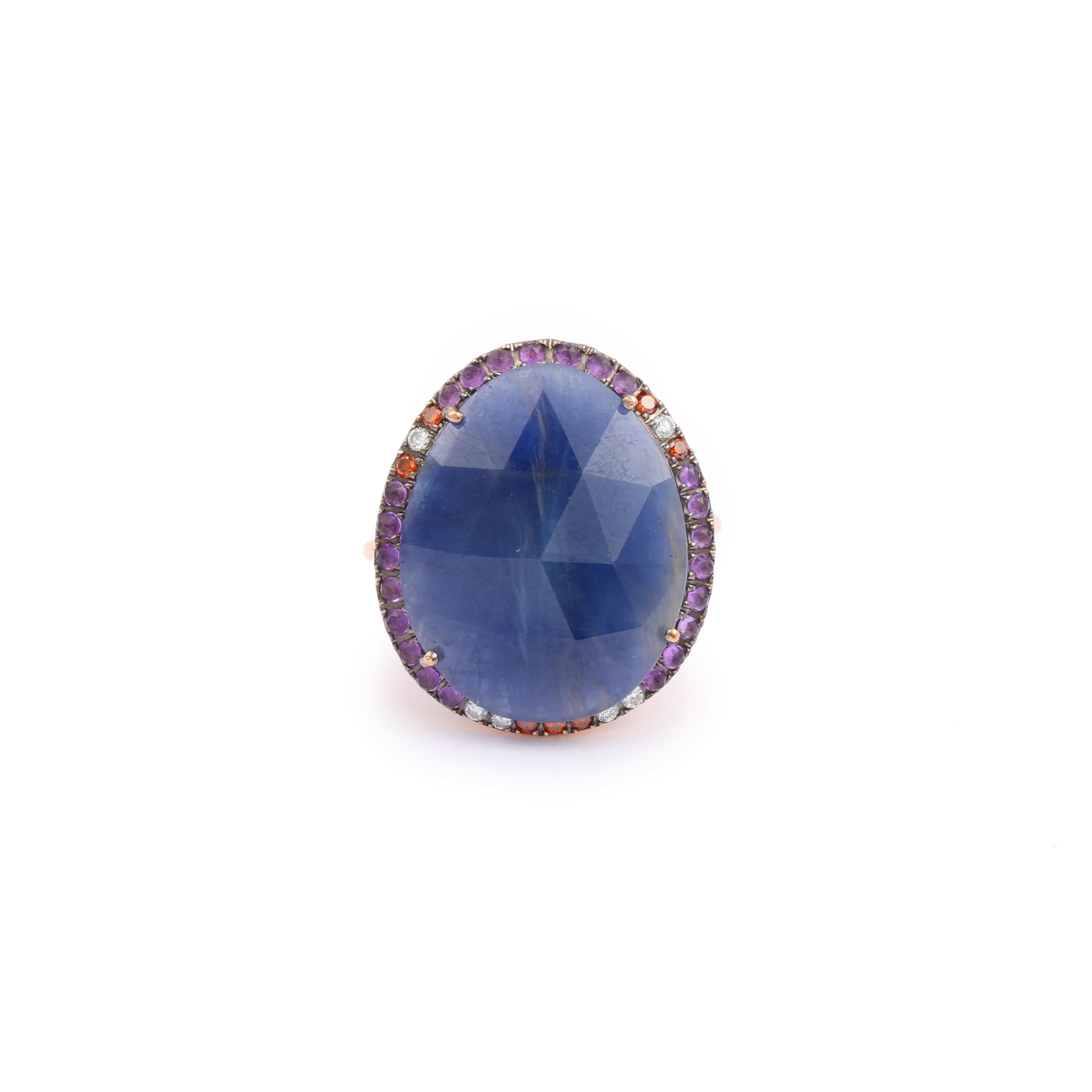Rose gold ring set with a faceted cabochon of sapphire root in a setting of diamonds, amethysts and red stones. 

Estimated weight of the sapphire : 19 carats

Total estimated weight of amethysts : 0.20 carats

Total estimated weight of diamonds :