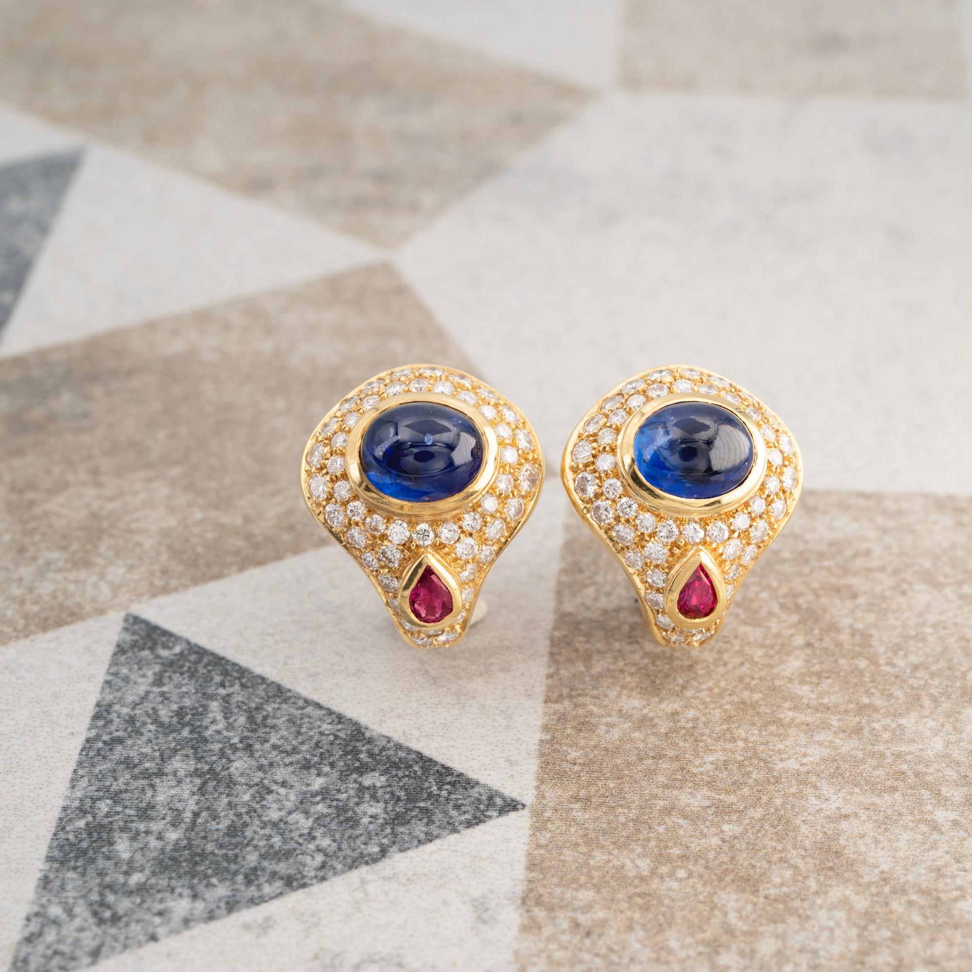 Magnifiques boucles d'oreilles de style bulgare, composées de saphirs cabochons bleus et de rubis en forme de poire. Chaque pierre précieuse a été sélectionnée pour la vivacité et l'intensité de sa couleur. Pour compléter ces pierres étonnantes, les