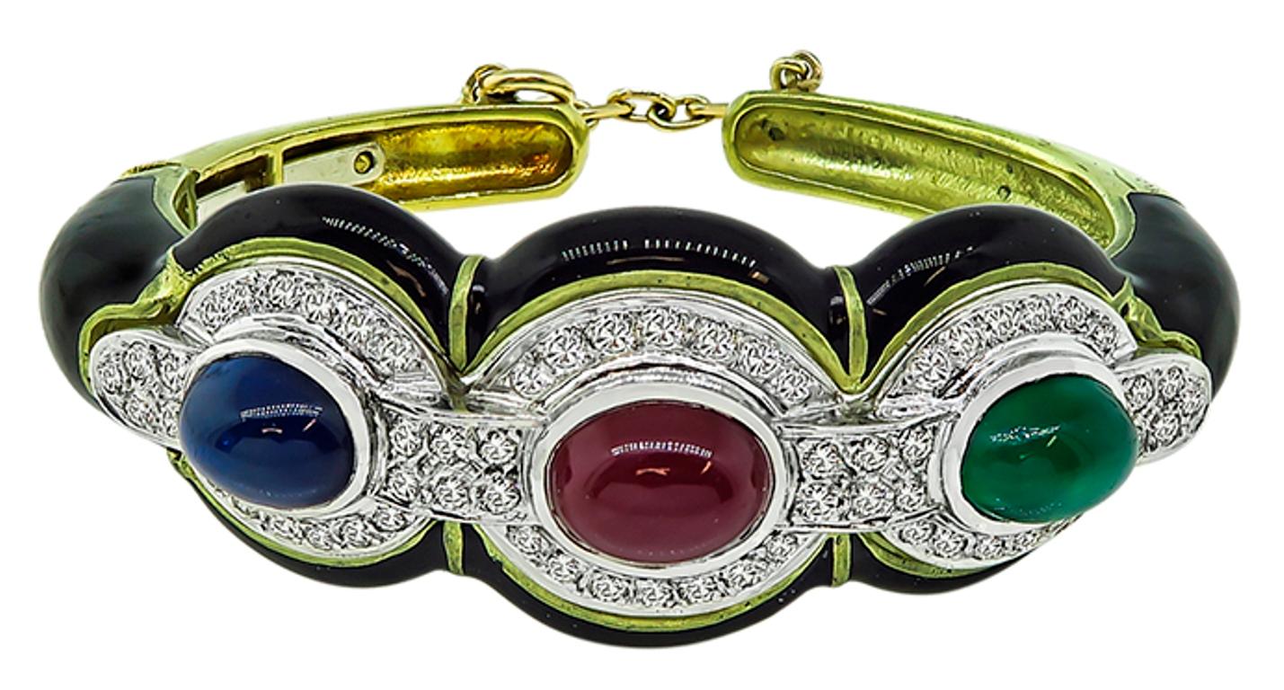 This elegant 18k yellow and white gold bangle is centered with a cabochon sapphire, ruby and emerald that weighs 1.50ct, 1.50ct and 1.00ct respectively. The precious stones are accentuated by sparkling round cut diamonds that weigh approximately