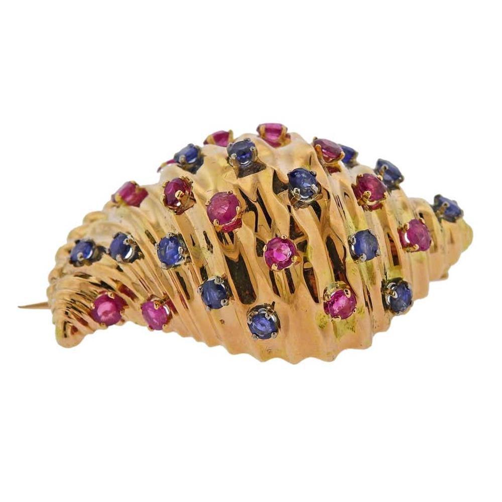 18k yellow gold seashell brooch, set with rubies and blue sapphires. Measures 47mm x 33mm. Marked 18k. Weighs 30.9 grams.
