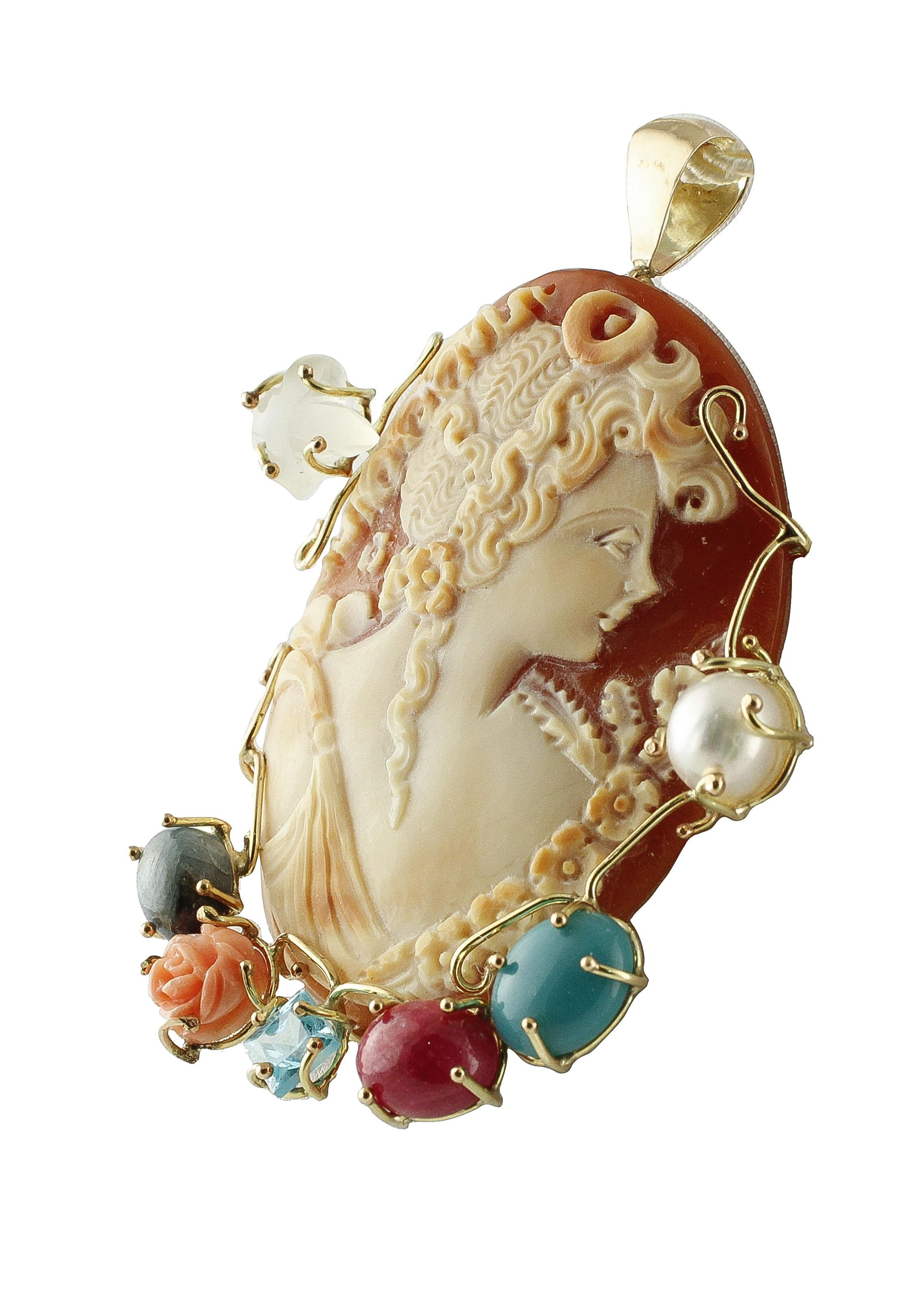 Gorgeous cameo pendant in 9K yellow gold structure embellished with blue sapphire, ruby, turquoise paste, blue topaz, rose shape pink coral, moonstone, and white glossy pearl.
Total Weight 17.10 g 
R.F iea
Pendant Dimentions 68 mm X 51 mm 
Cameo