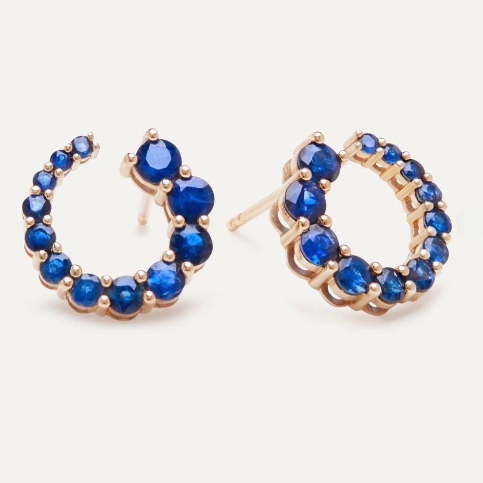 These sapphire round hoops are an exquisite fusion of elegance and timeless charm. Crafted from 14k gold, these hoop earrings are adorned with stunning sapphire gemstones. The sapphires, with their deep and captivating blue hue, add a touch of