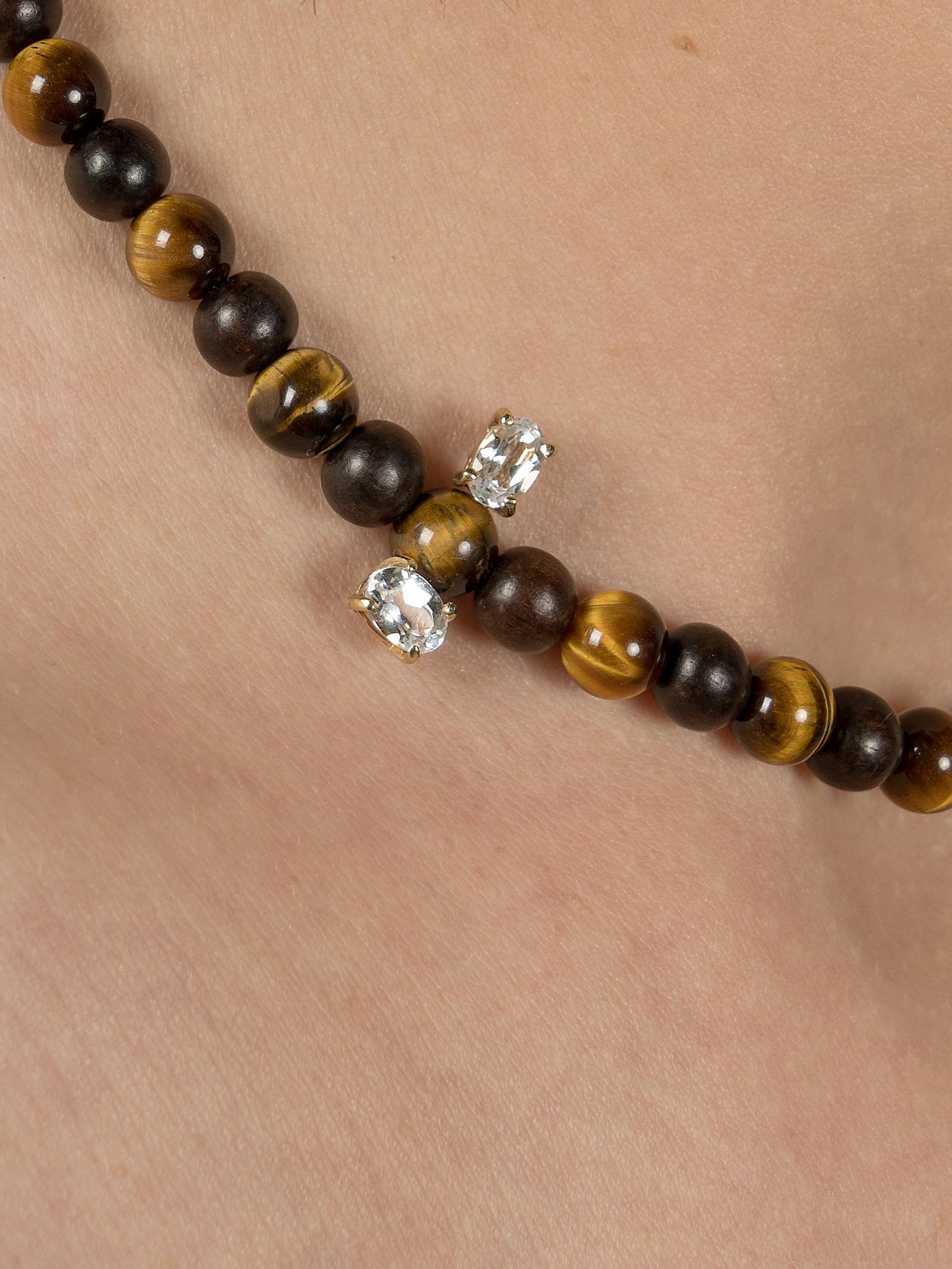 The Sapphire & Tiger’s Eye Island Collar in 9kt gold is a modern take on the bead necklace. The tiger’s eye beaded necklace features two oval sapphire gemstones set either side of the beads as to appear floating above and below the necklace. The