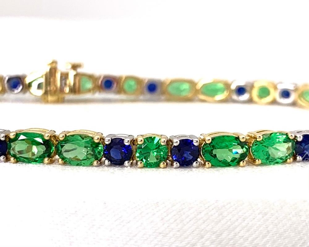 This beautiful two-toned tennis bracelet features bright, sparkling green tsavorite garnets and rich, royal blue sapphires set in 18k white and yellow gold. It is a little known fact that garnet, Janurary's birthstone, comes in a variety of colors,