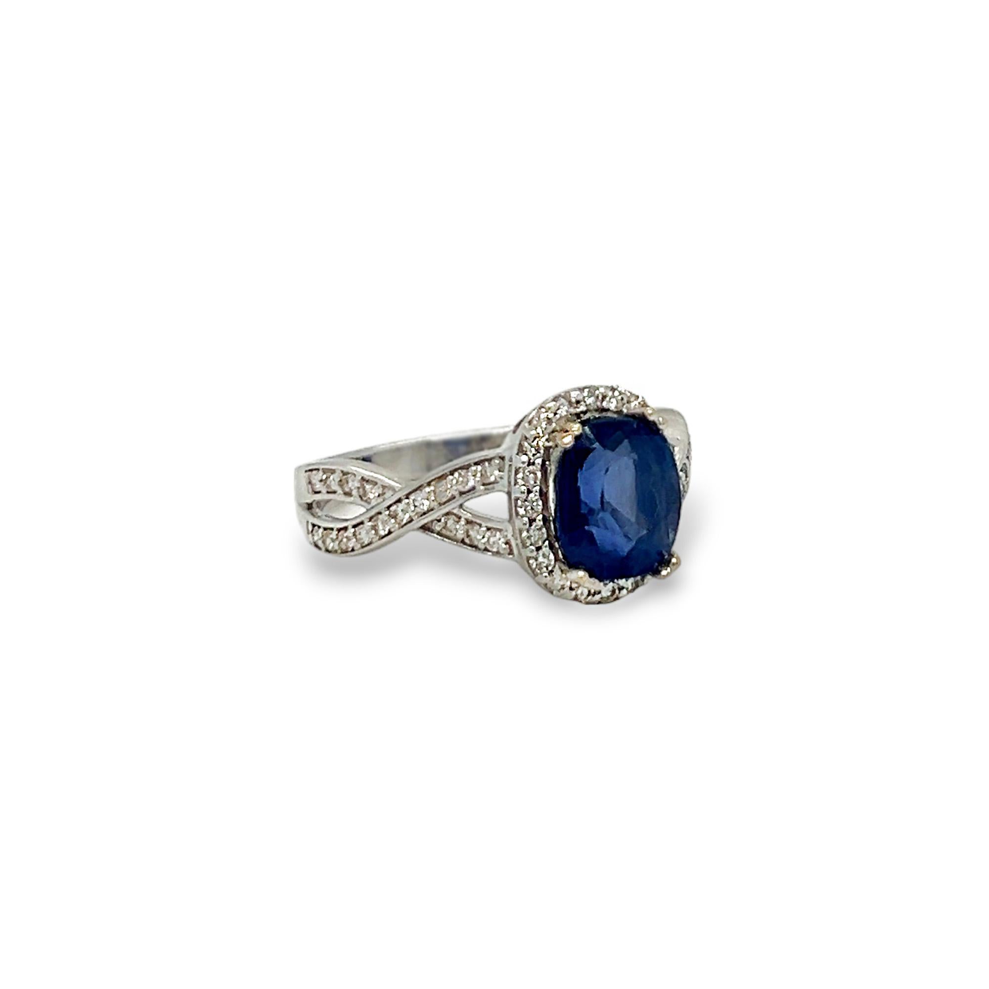 This statement ring stuns with 0.33 (total) carats of round diamonds adorning a gorgeous criss-cross band and a beautiful halo surrounding the oval center sapphire (2.55 carats). The diamonds are H/I color and SI clarity. Set in 14k white gold. Ring