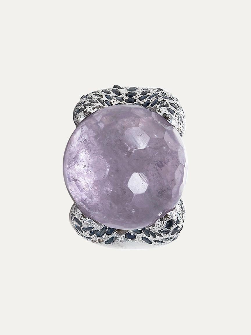 18kt – 750‰ white gold ring with 1 faceted spherical amethyst mea suring20.0mm diameter in the center, surrounded on both sides by blue sapphires. Polished finish


