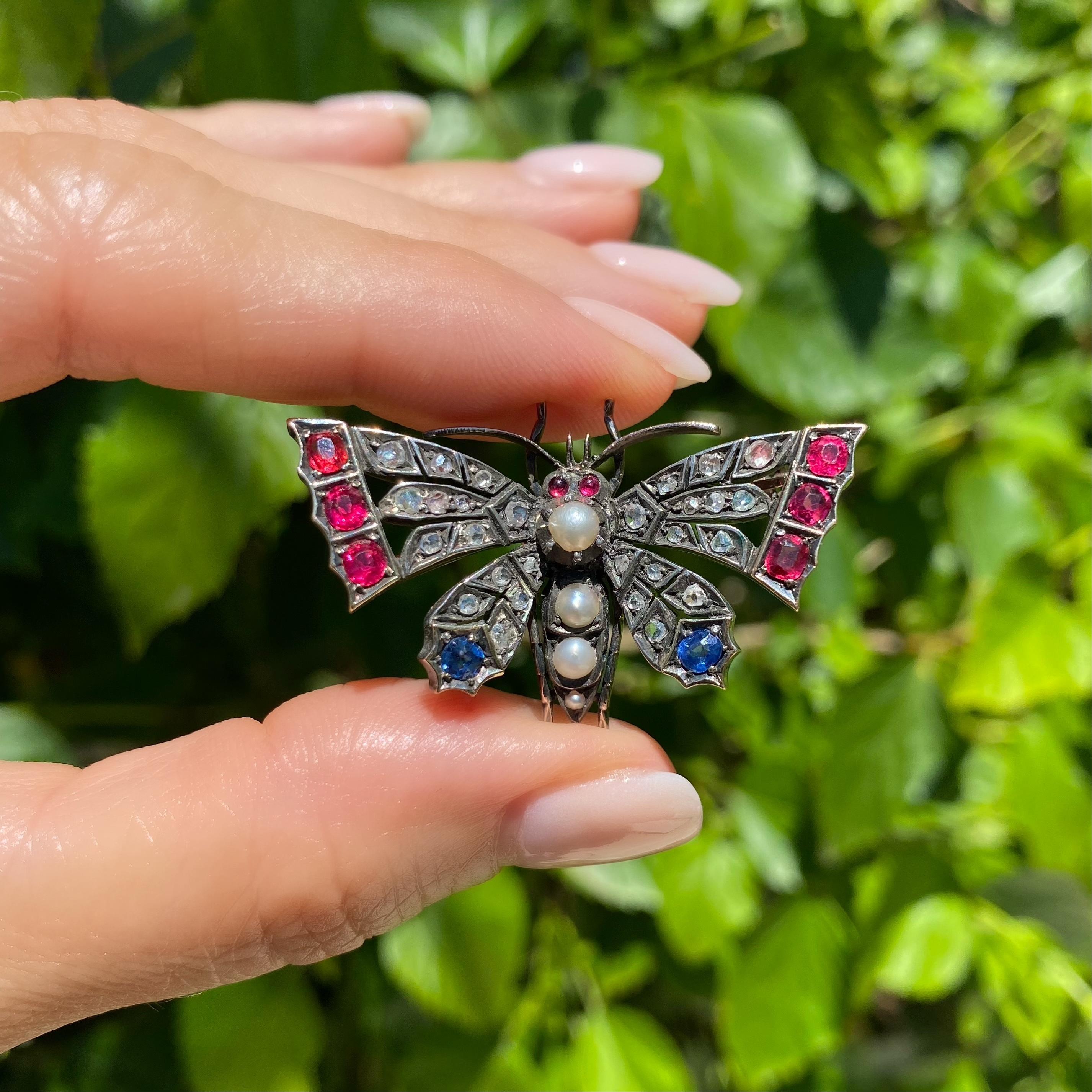A Wonderful Sapphire Ruby Pearl and Diamond Butterfly Brooch set with 28 Rose cut Diamonds approx. 0.35tcw, Pearls Sapphires and Simulated Rubies. Hand crafted in Silver on 14K Yellow Gold. Measuring approx. 1.66