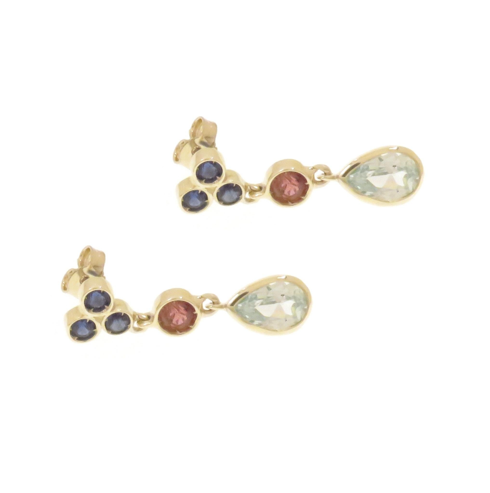 Lovely earrings featuring three gemstones: sapphires, pink tourmaline, blue topaz. Three round sapphires form a tringle at the ear lobe, the pink tourmaline in the middle is followed by a sparkling blue topaz drop, Crafted in 9 karat white gold. The