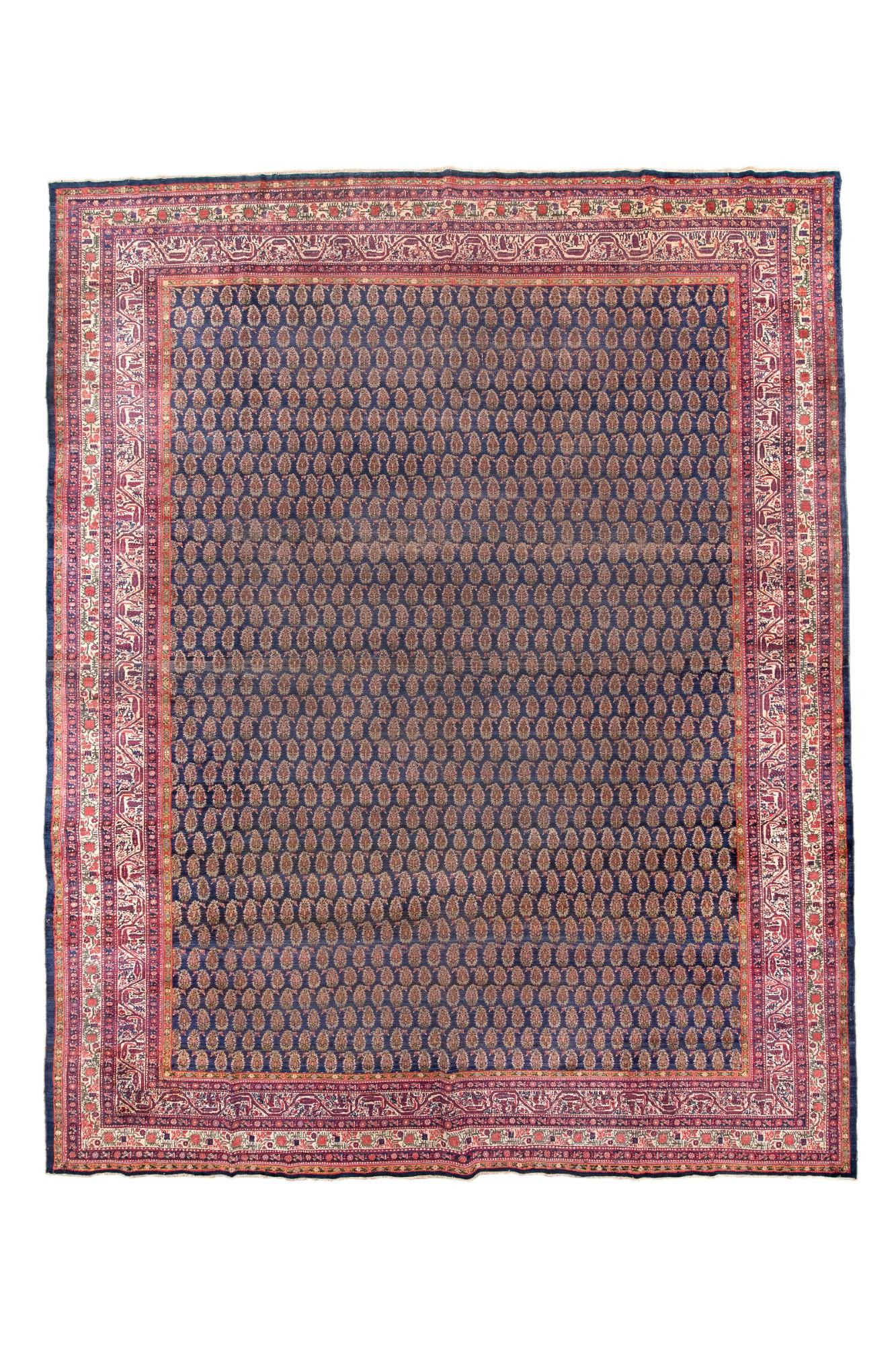 Millions of tiny botehs march left and right in alternating, reversing rows on a dark blue ground. The major sand border shows the characteristic Saraband trapezoidal meander with hanging botehs. Sand secondary border with fruit (pomegranates?) on a