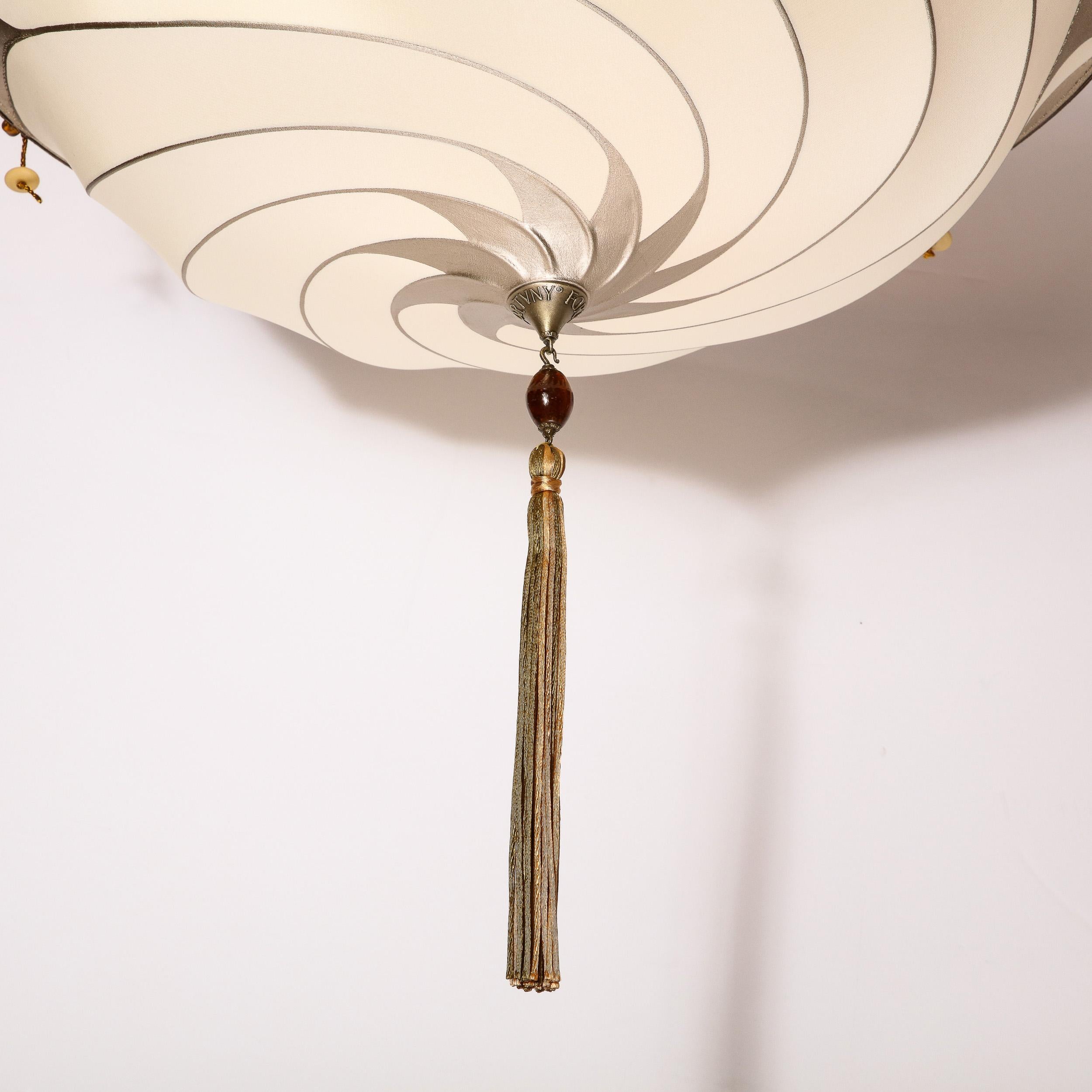 This elegant modernist Saracen shield chandelier was realized by the esteemed maker Fortuny during the latter half of the 20th century in Italy. It features a domed concave fabric shade emblazoned with swirling white gold striated detailing