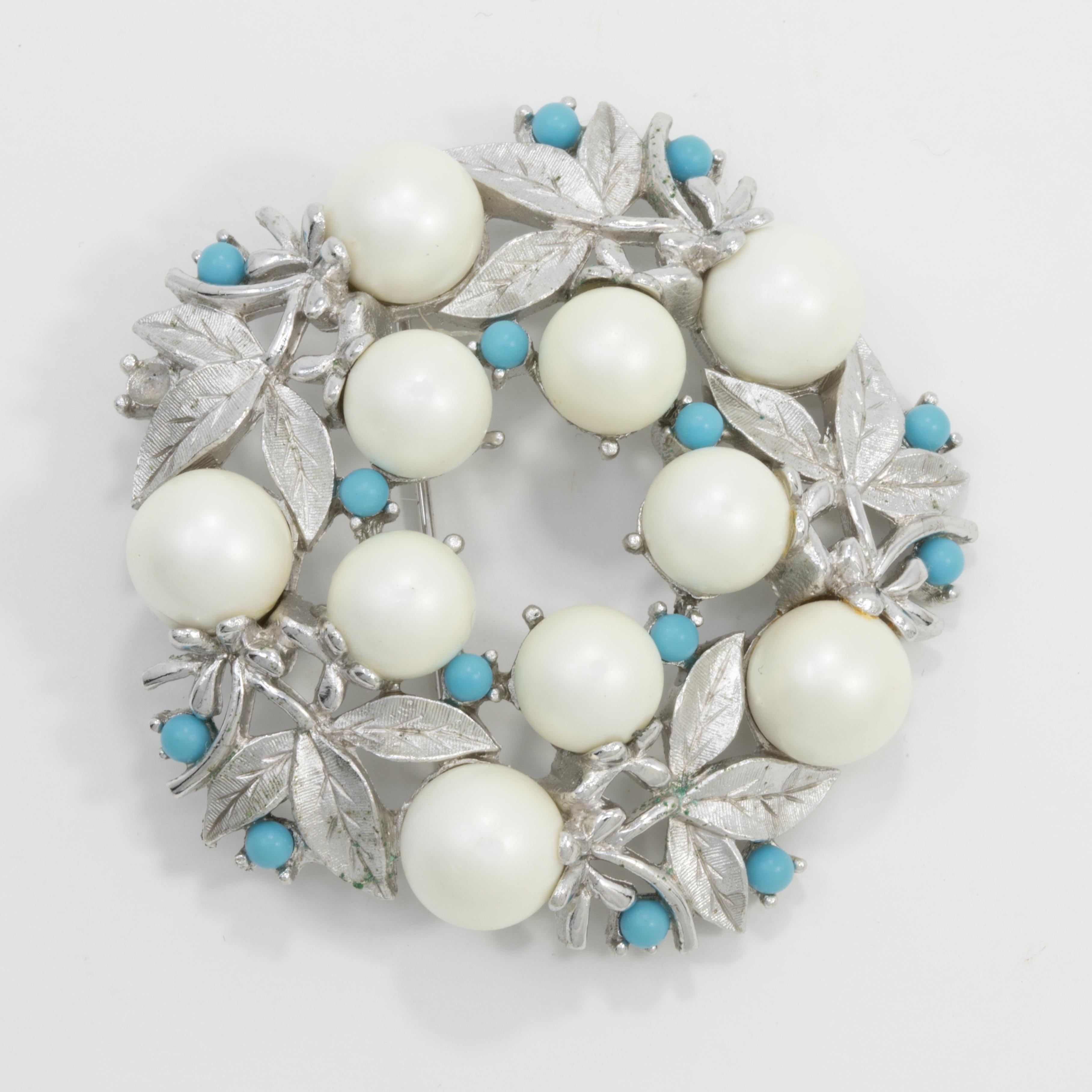 A stylish pin brooch by Sarah Coventry. Features faux pearls and turquoise-blue beads in a silver-tone floral wreath.

Marks, Hallmarks, Signatures: Sarah Cov