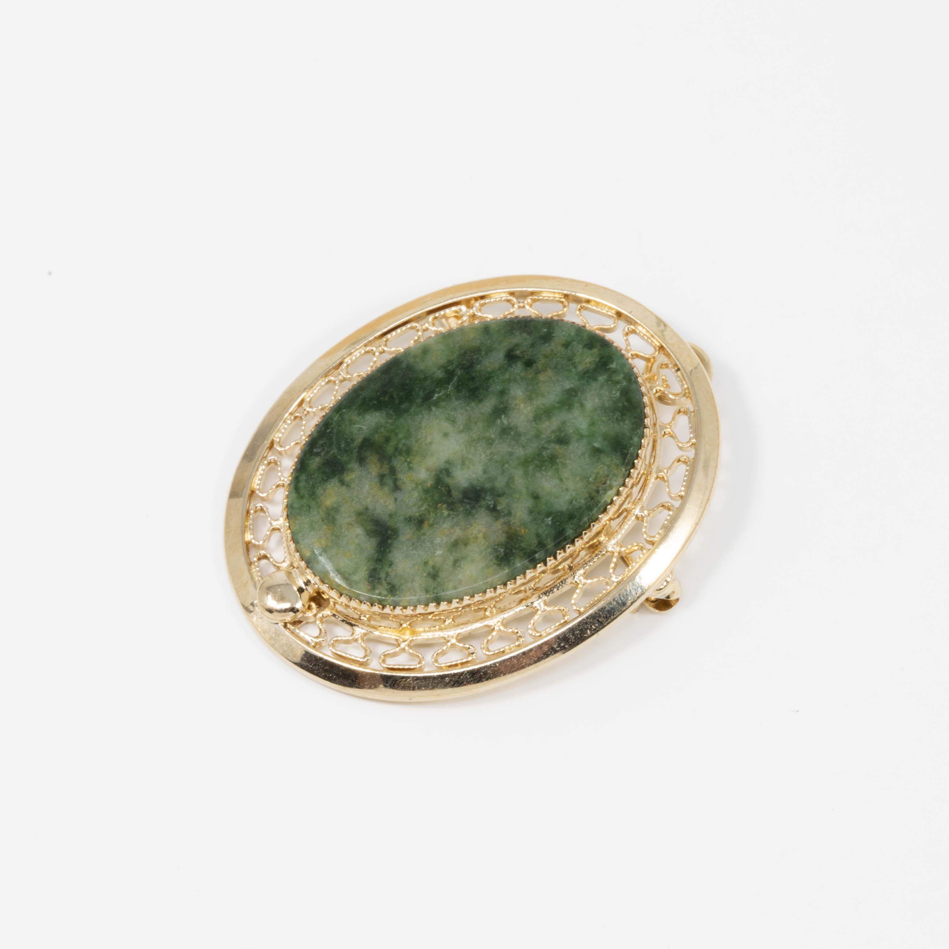 A pin/pendant by Sarah Conventry, featuring a marbled green oval gemstones set in an open back decorative golden bezel.

12K gold filled.

Circa Late 1900s.

Tags, Marks, Hallmarks: Sarah Cov, 1/20 12K GF