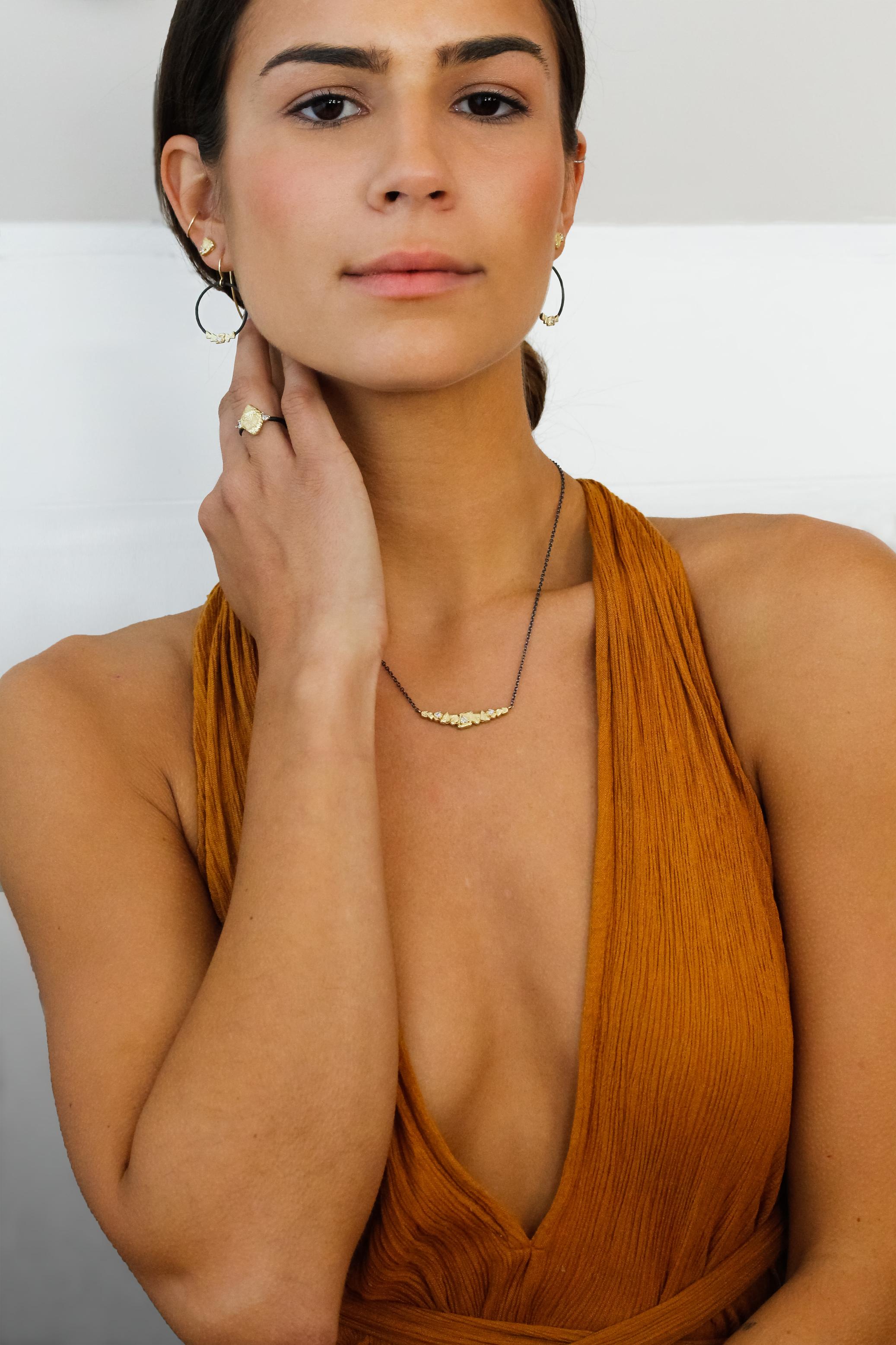 Trigon Bar Necklace handcrafted by acclaimed jewelry artist Sarah Graham showcasing three shimmering trillion-cut white diamonds totaling 0.20 carats, set in a beautifully-textured 18k yellow gold bar inspired by both the natural beauty of Colorado