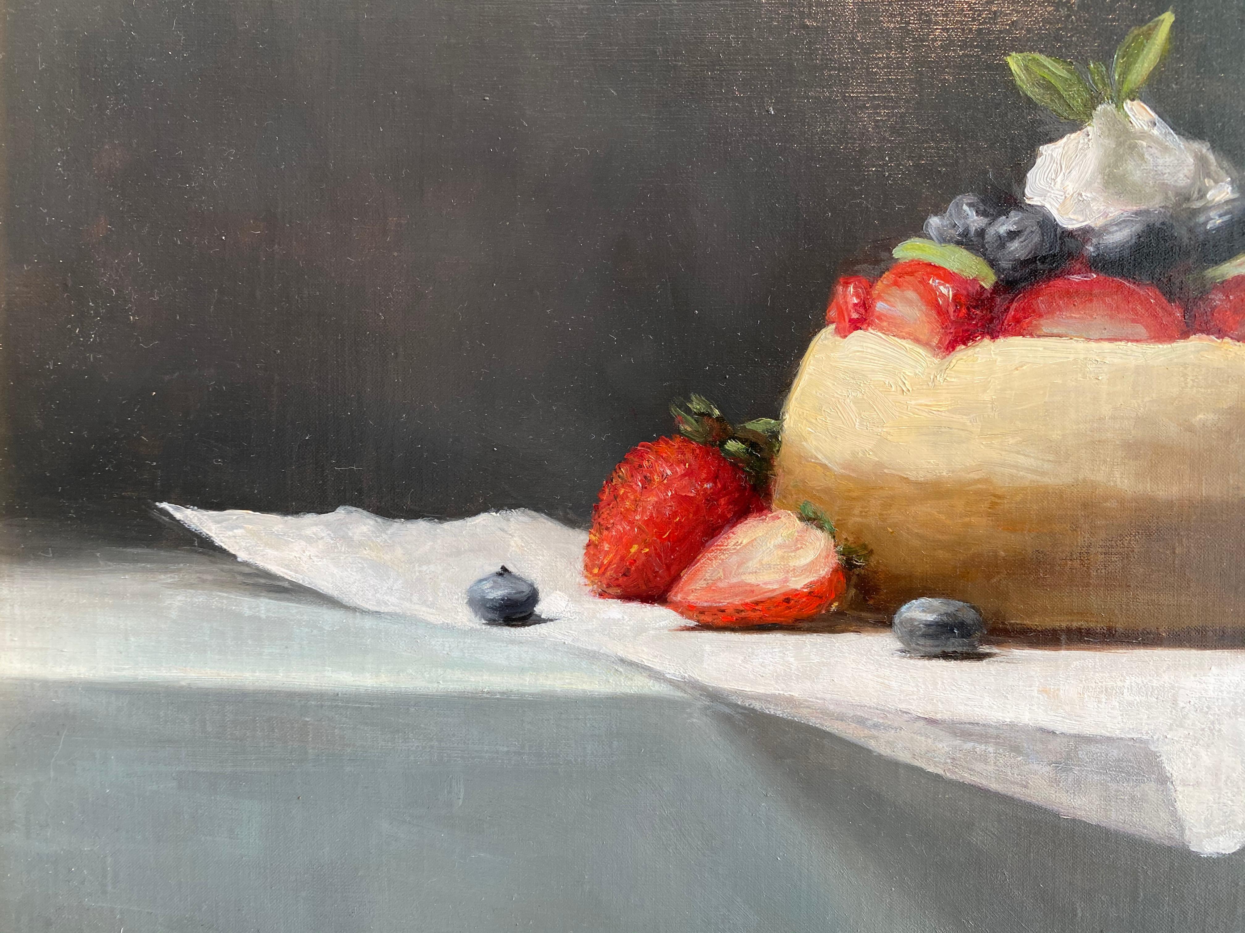 A Still life painting of a small cheesecake, adorned with strawberries, blueberries, and cream. Placed upon a layer of parchment paper, against a grey backdrop.  Sarah Lamb is known for her poetic still lifes that utilize classical painting