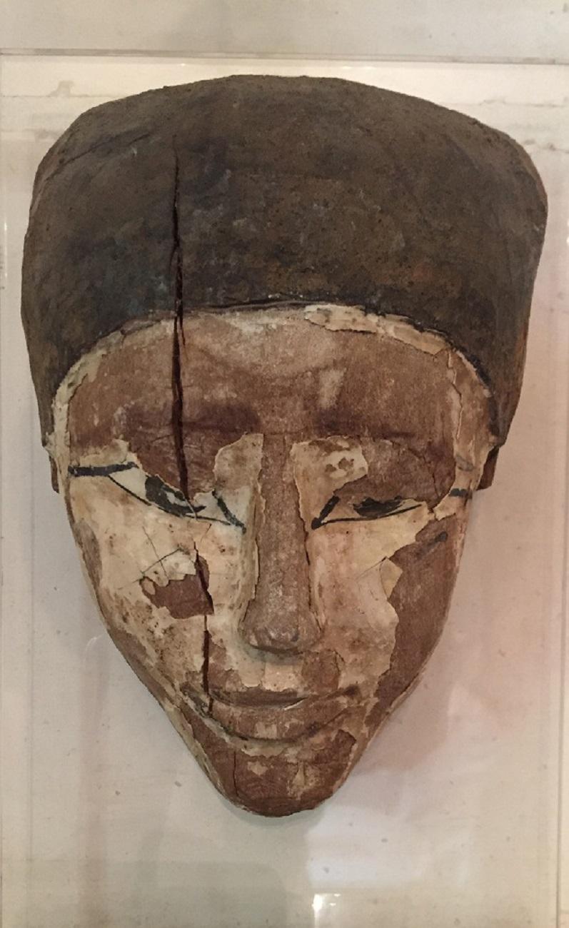 This Sarcophagus mask was probably made in the reign of Seti (1300-1200 B.C.). It is skilfully sculpted from cedarwood and still has fragments of its original painted stucco. The facial expression is as appealing as it would have been placed on the