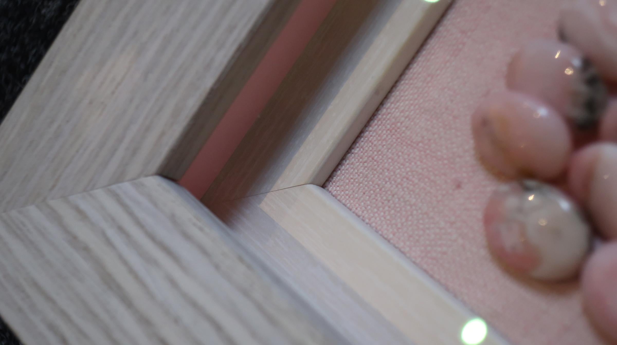 Ciuffo in rafia e punto di raso geometrico con pietre rosa.