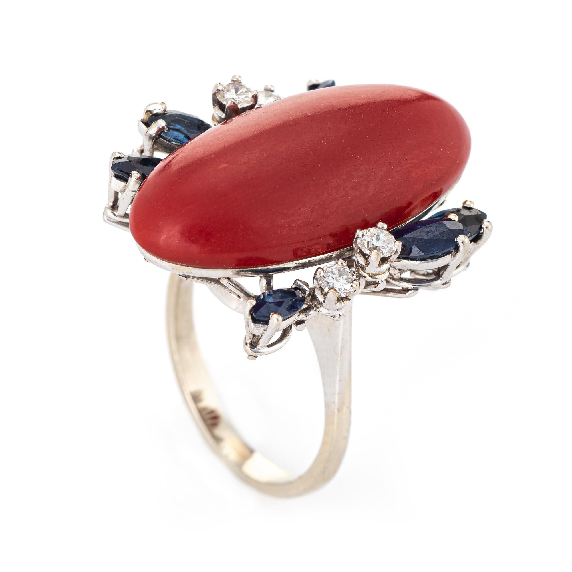 Stylish vintage Sardinian red coral, sapphire & diamond cocktail ring (circa 1950s to 1960s) crafted in 18 karat white gold. 

Sardinian red coral measures 26mm x 12mm (estimated at 10 carats) is accented with 6 estimated 0.10 carats blue sapphires