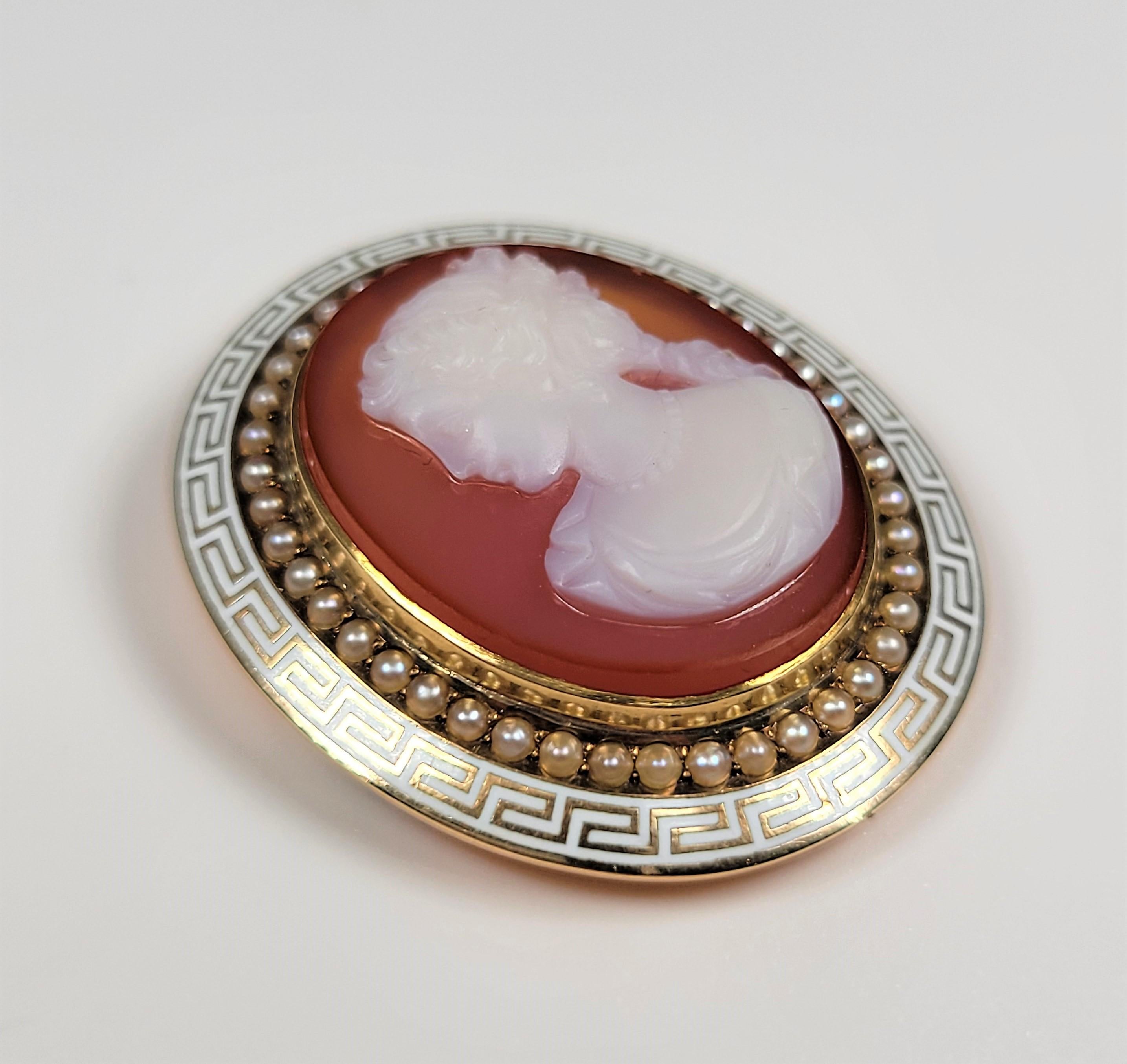 Composed of 14 karat yellow gold, this unusual sardonyx cameo features a row of seed pearls all encircled by white enamel in a Greek key pattern. 