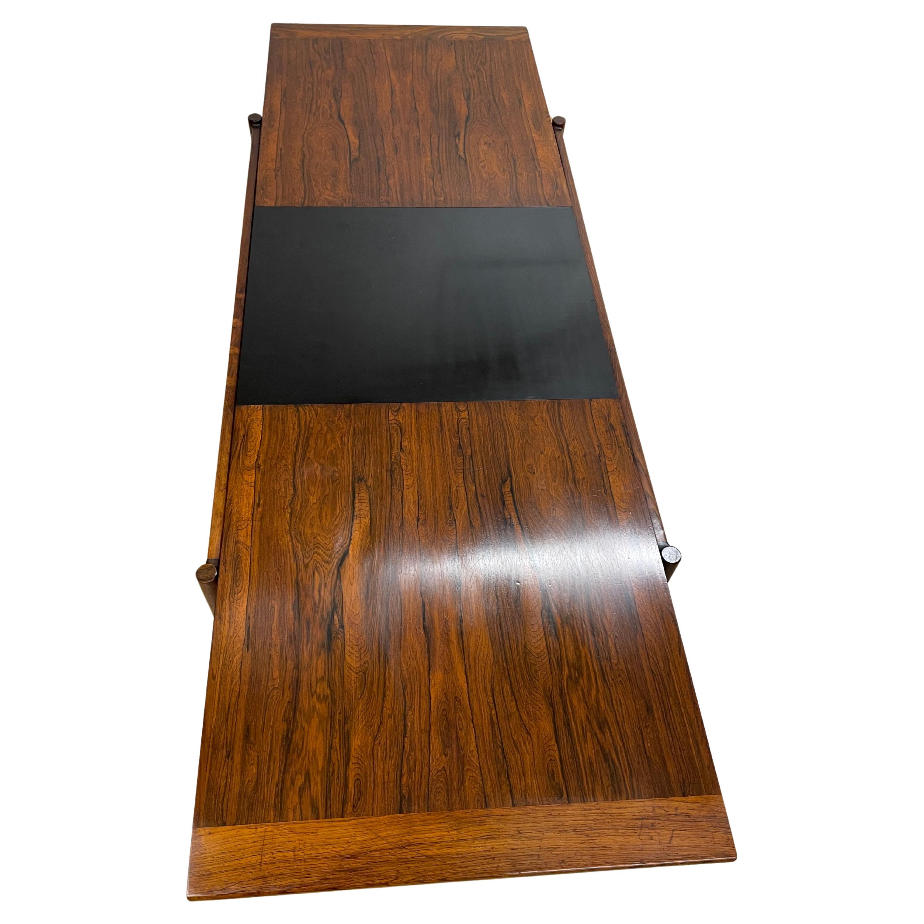 Sari coffee table by Torbjorn Afdal for Bruksbo, 1960's design in jacaranda. A clever and very nice device allows the table to be extended from 135 to 185 cm with a center part in black formica which goes from underneath to the top. This also brings