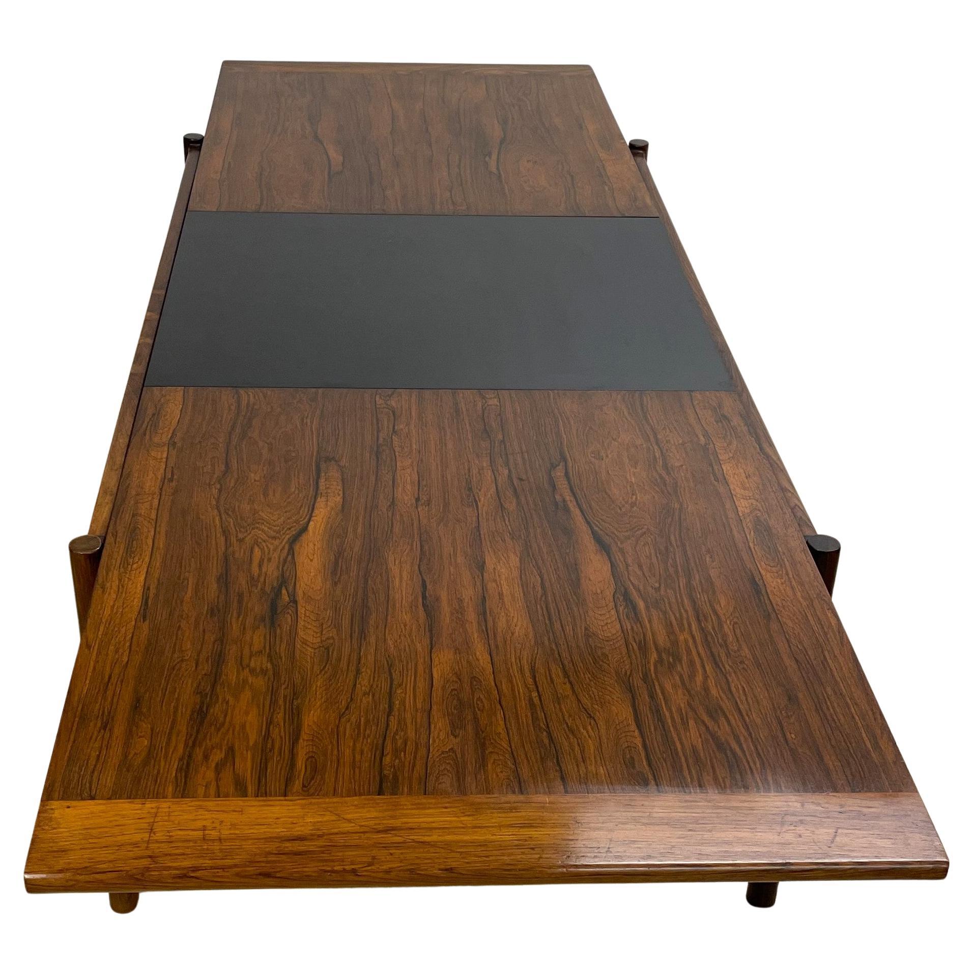 Sari coffee table by Torbjorn Afdal for Bruksbo, 1960's design in jacaranda. A clever and very nice device allows the table to be extended from 135 to 185 cm with a center part in black formica which goes from underneath to the top. This also brings