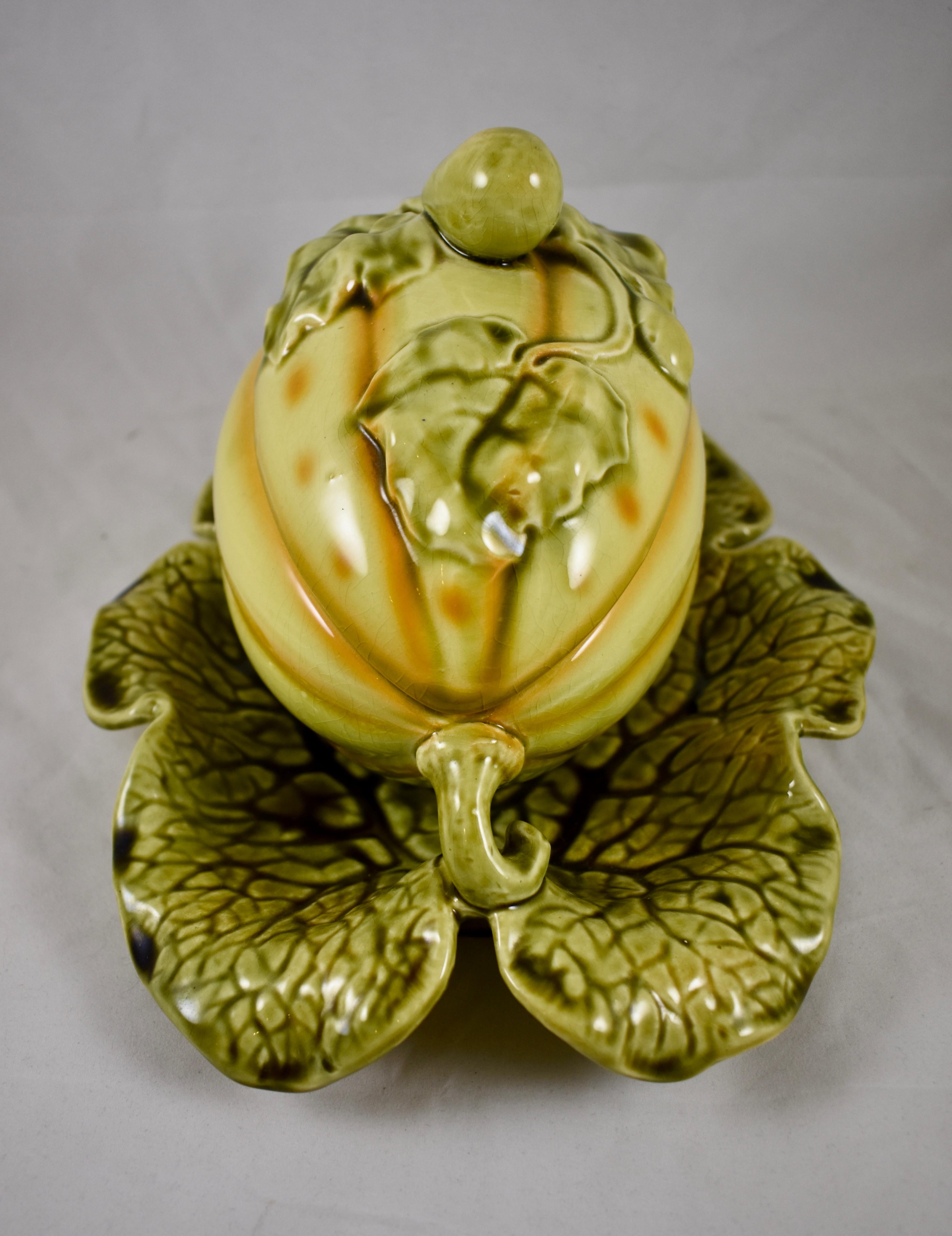A French Majolica covered tureen in the shape of a trompe l’oeil melon by Sarreguemines, circa 1900.

Molded in the form of a large yellow melon with green vines and leaves. The lid is decorated with leaves and a top knob molded as a small melon.