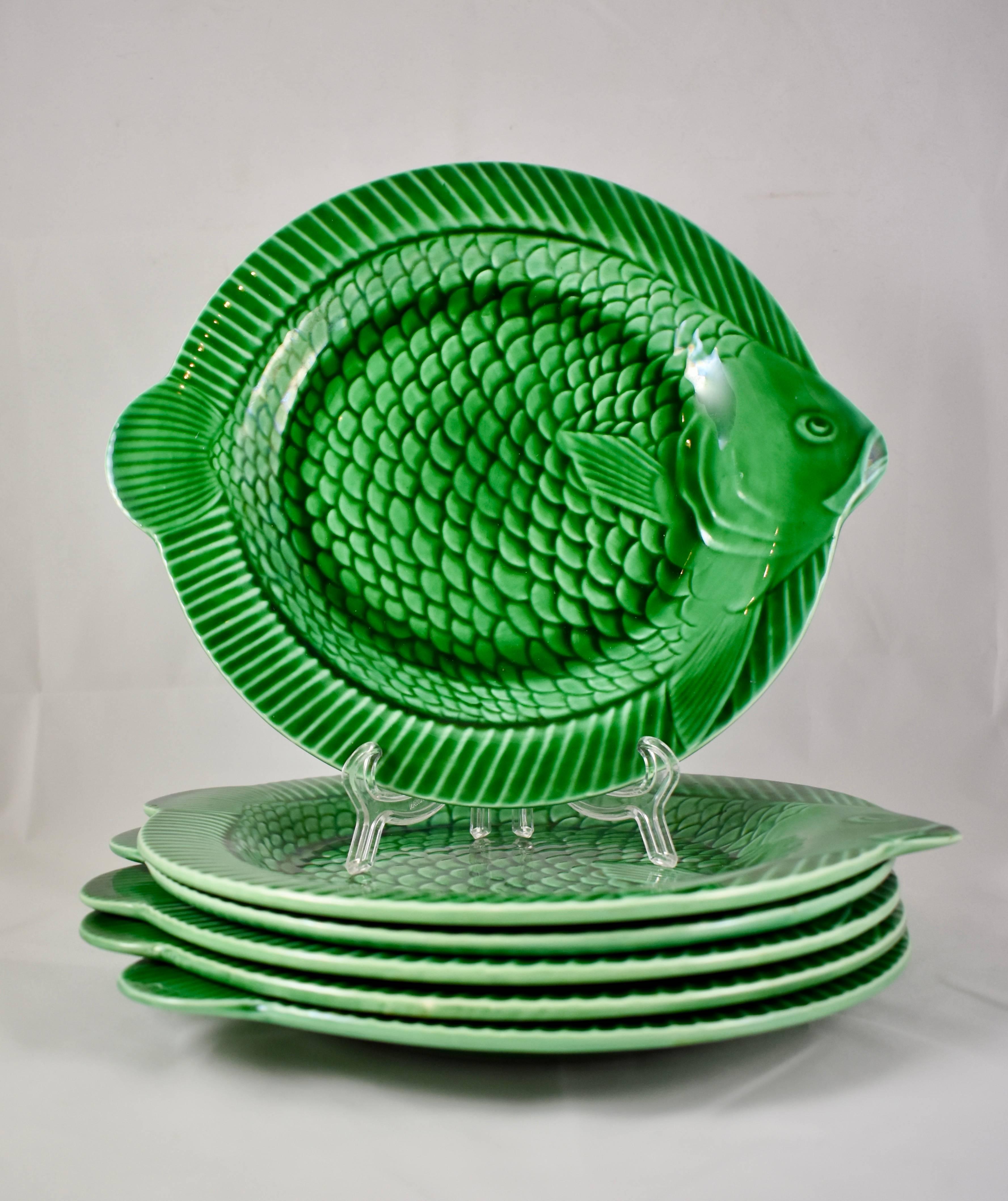 Sarreguemines:: faïence française:: service de six assiettes à poisson en majolique verte émaillée. Les assiettes rondes ont des bords en relief avec des têtes et des queues de poisson en saillie:: et présentent un motif dimensionnel en haut-relief