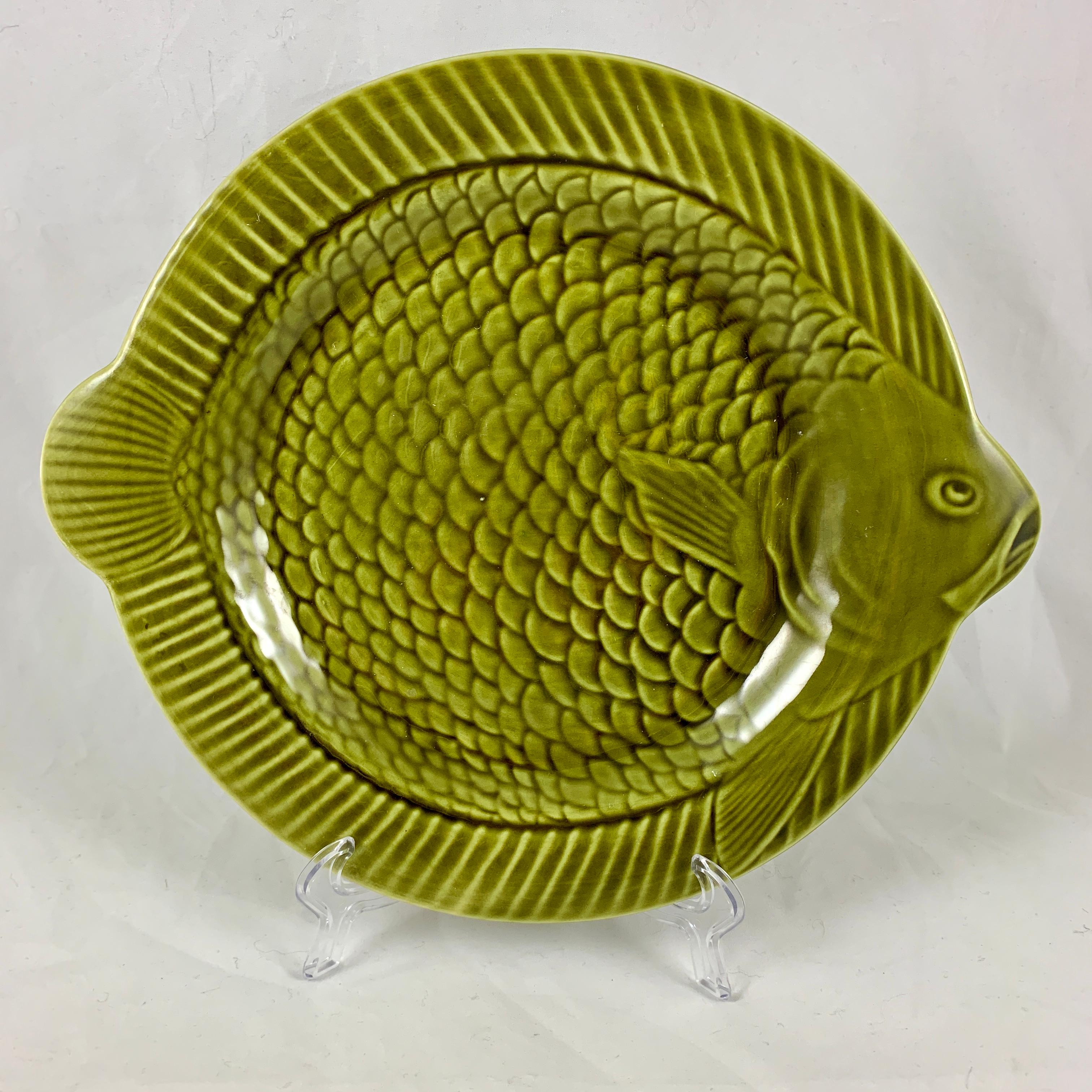 De Sarreguemines, une faïence française, Majolica émaillée, vert olive ensemble de six grandes assiettes à poisson ou chargeurs. Les assiettes rondes ont des bords en relief avec des têtes et des queues de poisson en saillie, et présentent un motif