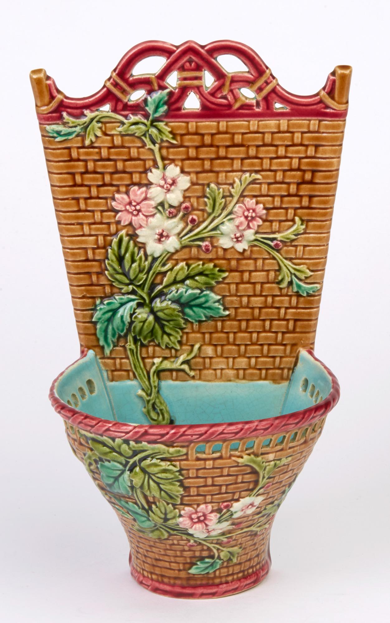 A very fine antique French art pottery Majolica wall pocket by Sarreguemines and dating from circa 1880-1890. The lightly pottery wall pocket is modeled as a basket with a pierced rim containing flowers which are applied to the front and to the back