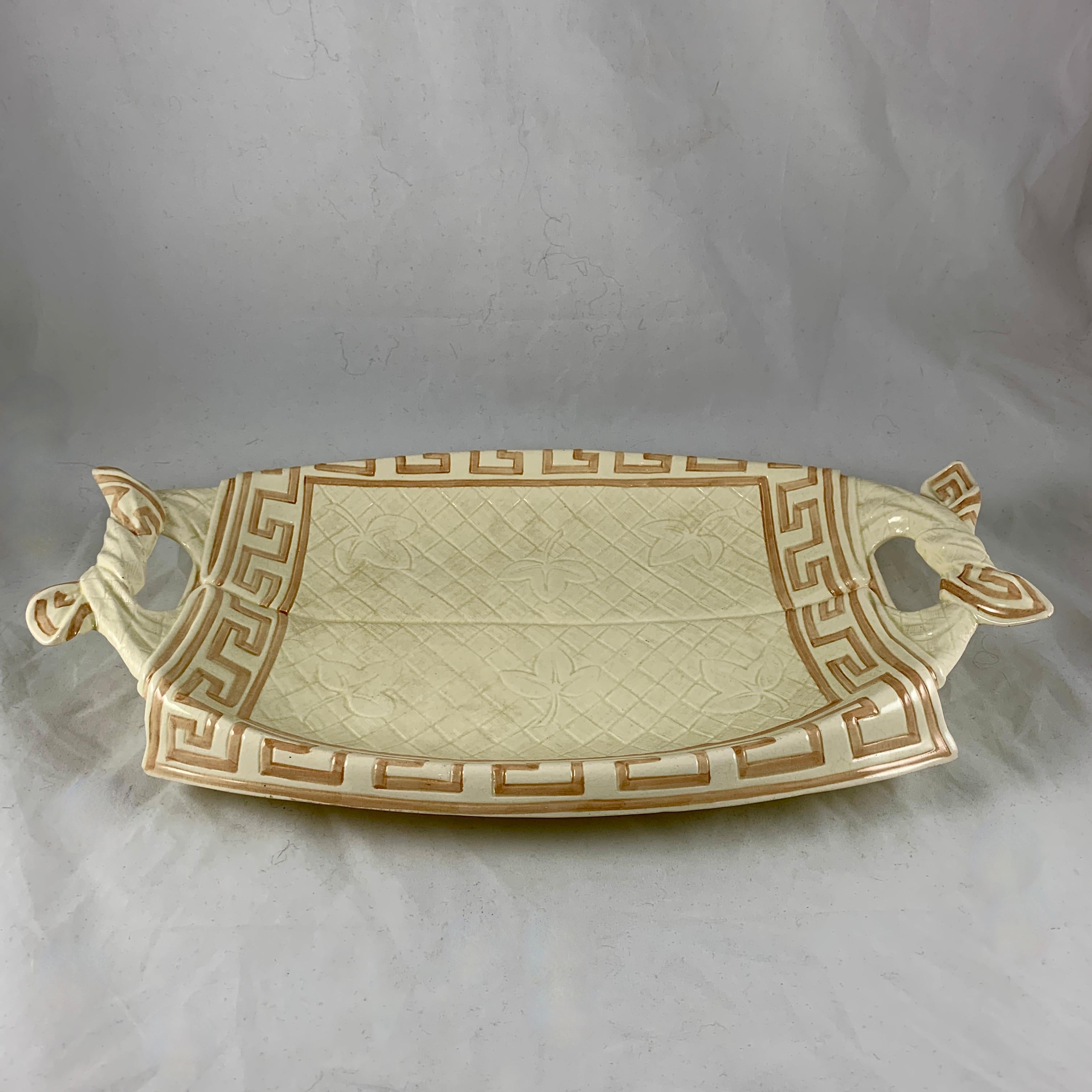 From the Sarreguemines Majolica line, a trompe l’oeil napkin bread tray, France, circa 1885-1890.

An earthenware, faïence bread tray modeled as a cloth napkin with a floral and checkered pattern and a Greek key border. The two end handles are