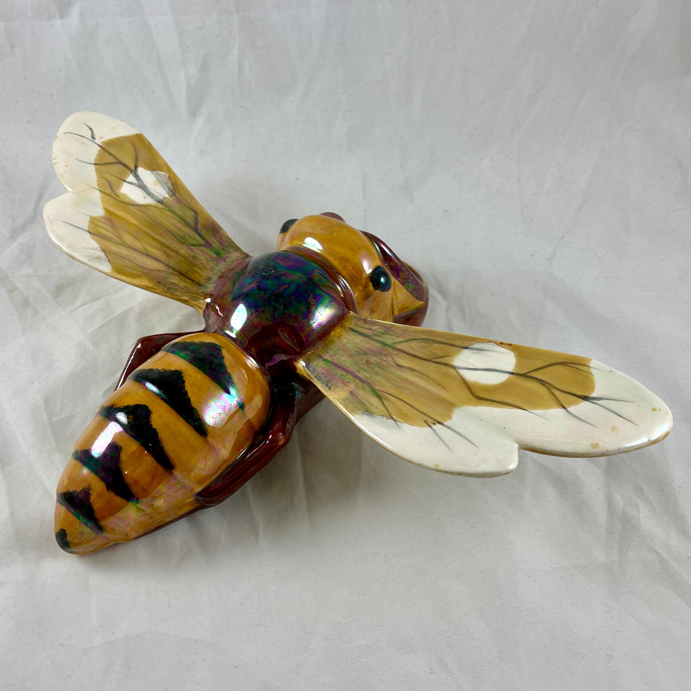 
From the French faïencerie Sarreguemines, a Bee shaped wall pocket, circa 1910.

A majolica glazed earthenware bee or wasp formed as a wall pocket. This is the largest size of mold number 4402. 

The body of the bee is finished in yellow ochre and