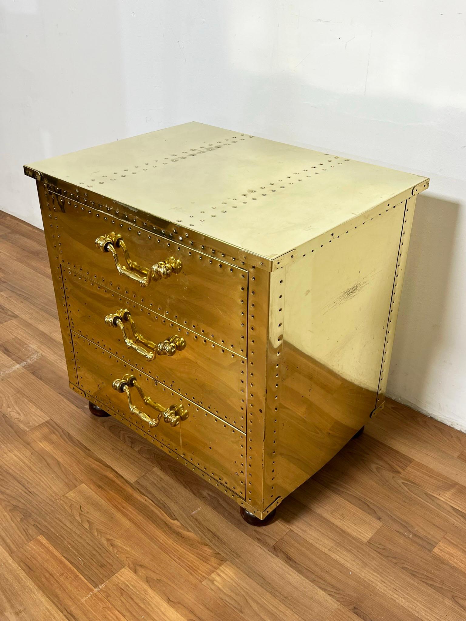 Brass clad three drawer chest with overhanging top and wooden bun feet by Sarreid, circa 1970s.