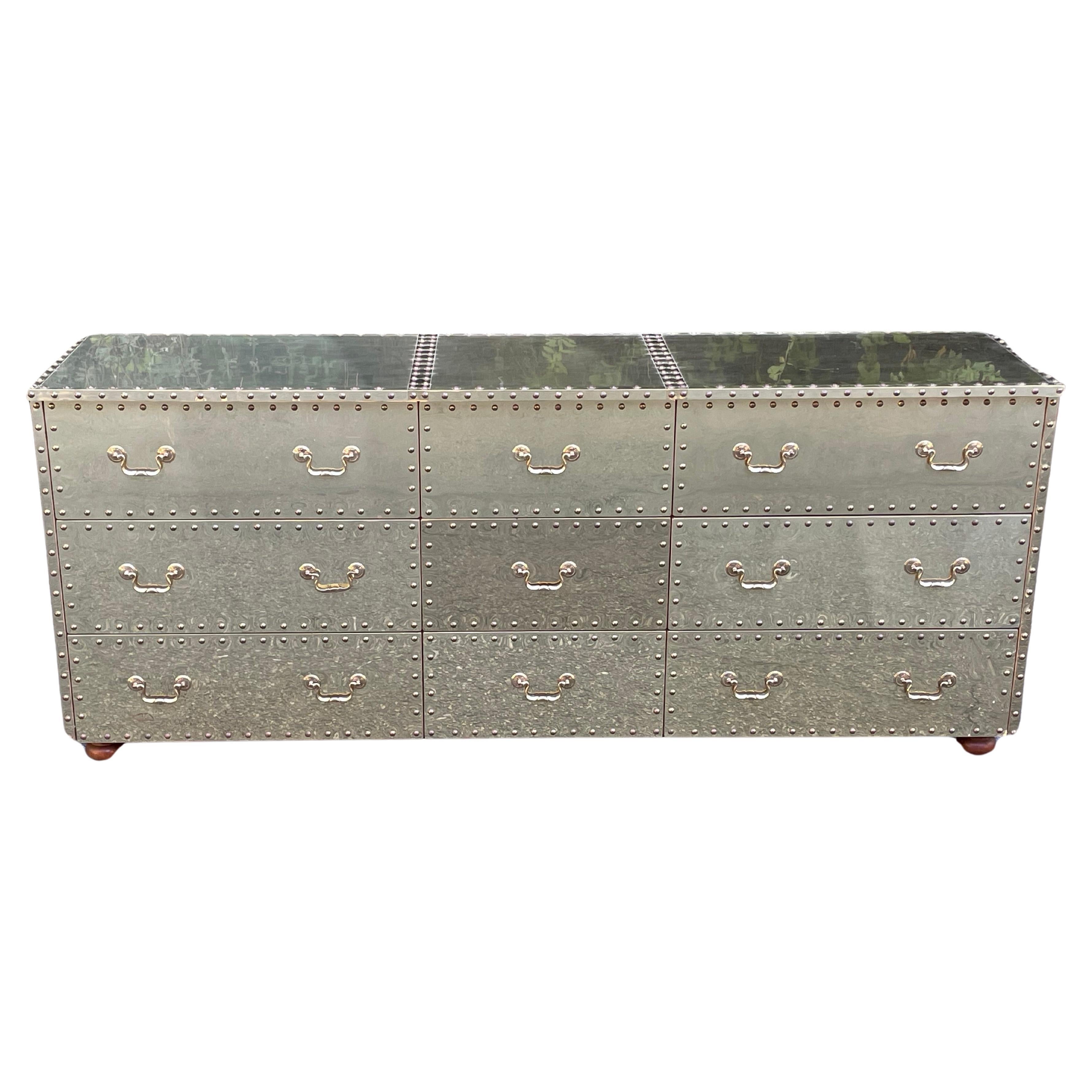 Striking mid-century brass clad nine-drawer dresser with nailhead trim by Sarreid Ltd. Circa 1970s.

Clad on three sides with solid brass sheeting, this triple dresser is one of the most sought after of the vintage Sarreid designs. It really makes a