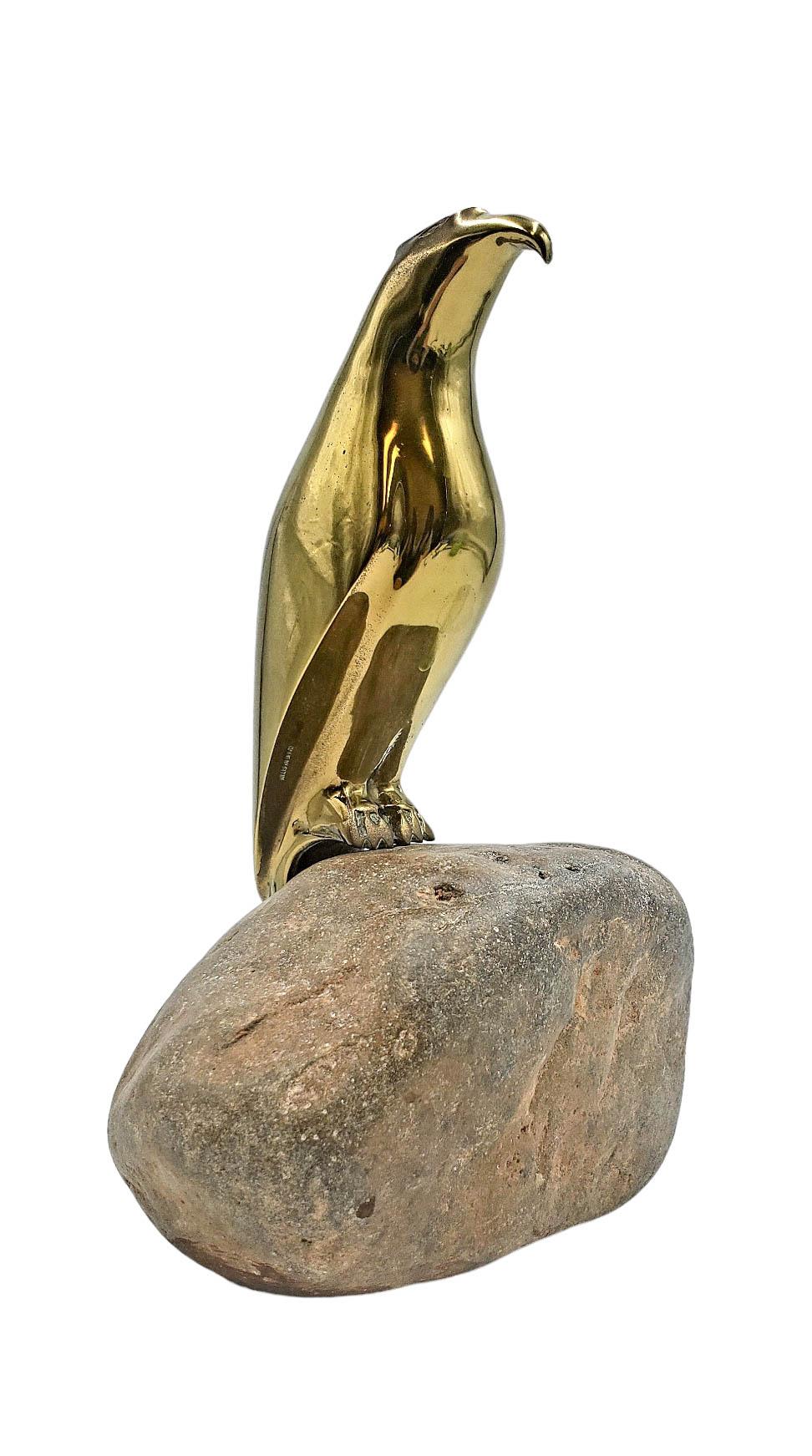 Sculpture de Sarreid, Espagne. Un faucon en laiton hautement poli perché sur une base en roche naturelle. Le faucon est représenté par des lignes épurées et stylisées, caractéristiques du design moderne du milieu du siècle dernier, qui mettent en