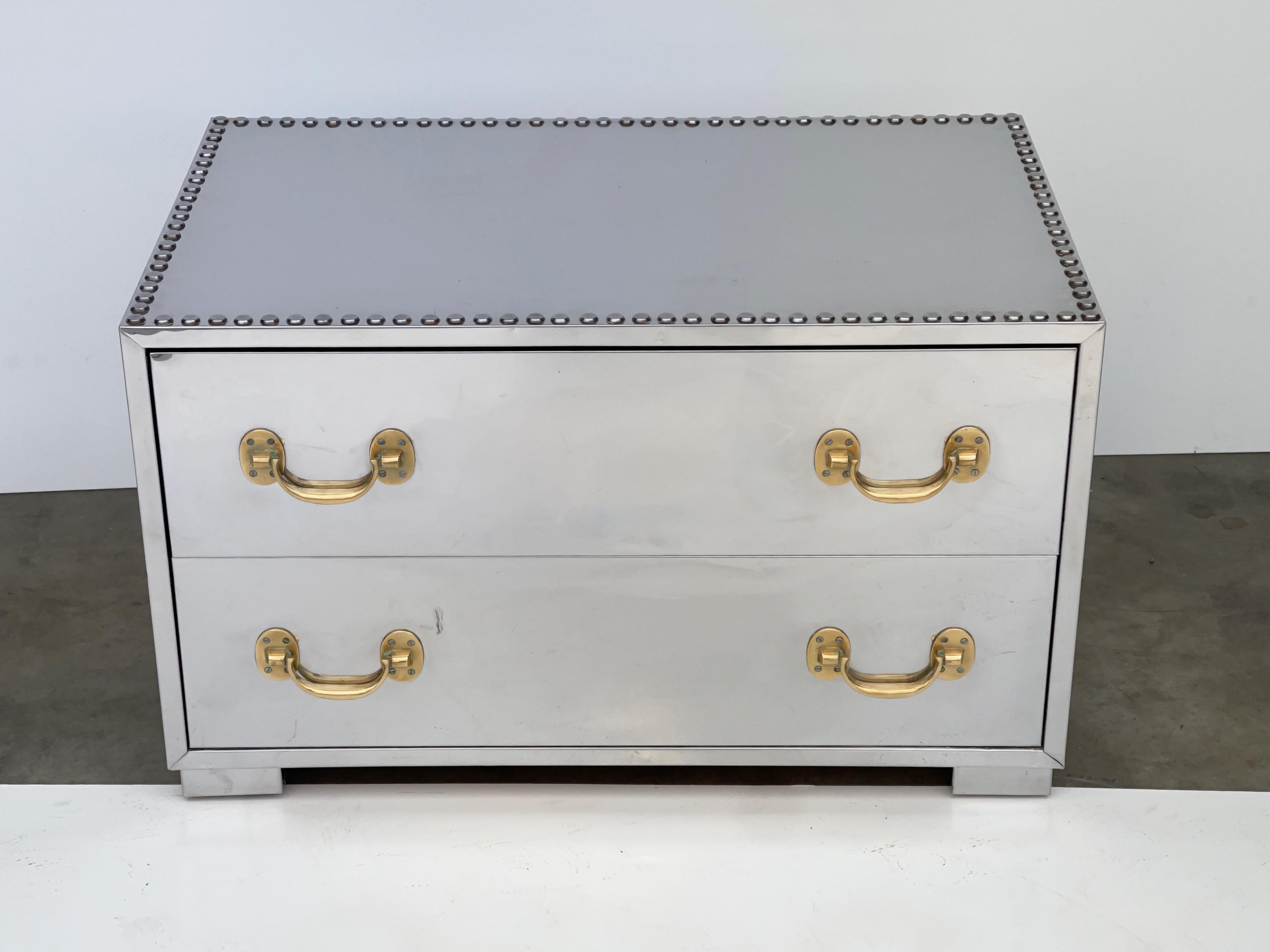 Vintage 1960s mirror polished stainless steel clad Campaign chest of two drawers with solid brass pulls by Sarreid of Spain. Finished on the backside as well for floating within your room. Drawers have red faux-velvet flocking. Top outlined with