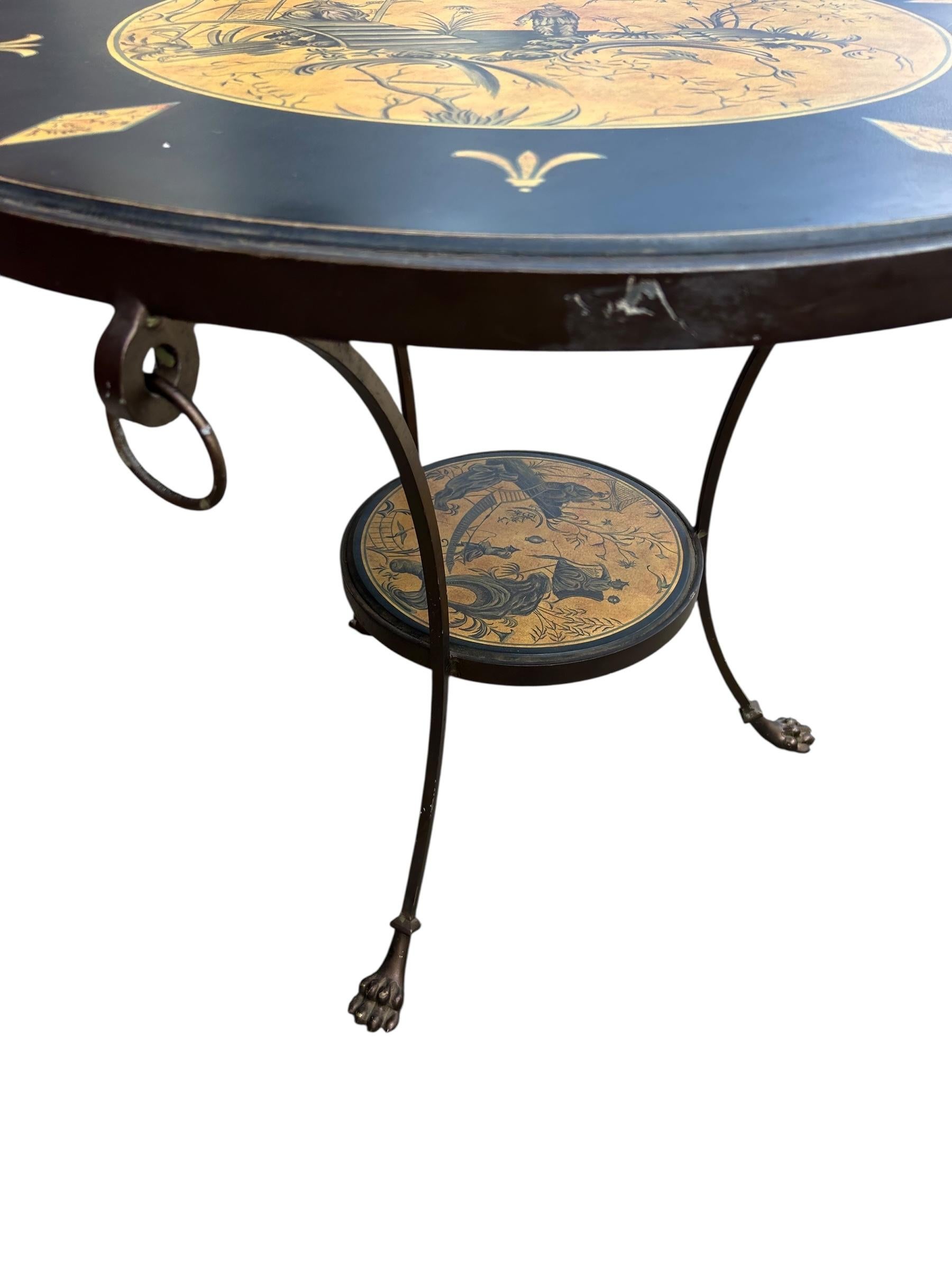 Sarreid Round Chinoiserie Gueridon Side Table. Brass framed table with a circular painted center with chinoiserie decoration depicting men in fields.
The circular brass top with three rings around the top and paw feet. Sarreid label attached to the