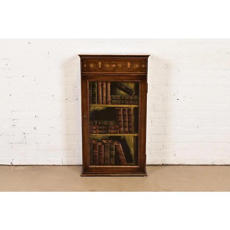 A gorgeous English Regency or Sheraton style hand painted bookcase featuring a trompe-l'œil painting of books on the door.

By Sarreid Ltd.

Circa Late 20th Century

Measures: 21
