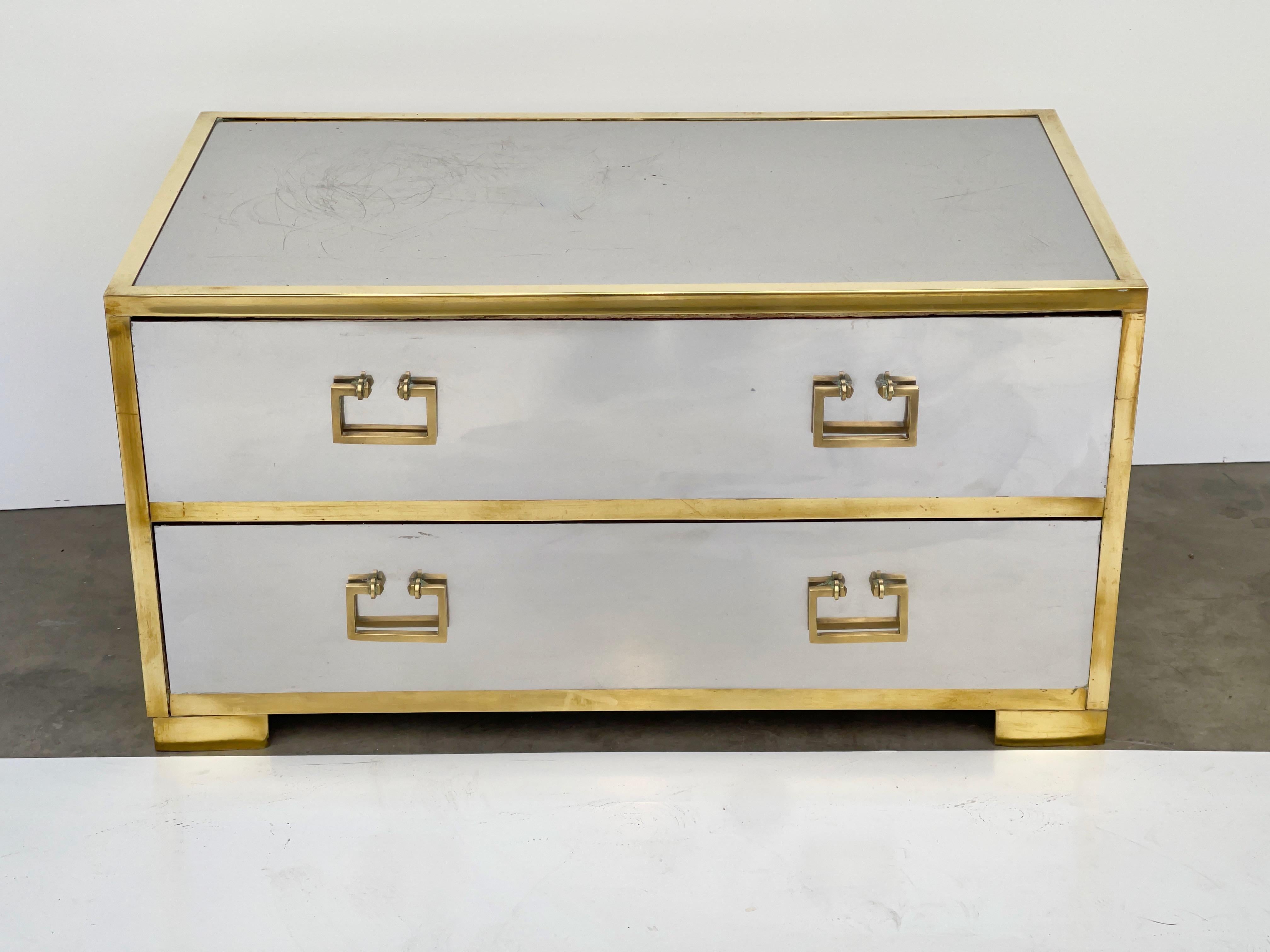 Sarreid of Spain geometric two-drawer footed low chest clad in mirror polished stainless steel and trimmed in brass with solid brass greek key style pulls and side handles. Vintage 1960's Hollywood Regency.
Wood drawers clean inside.
Finished on