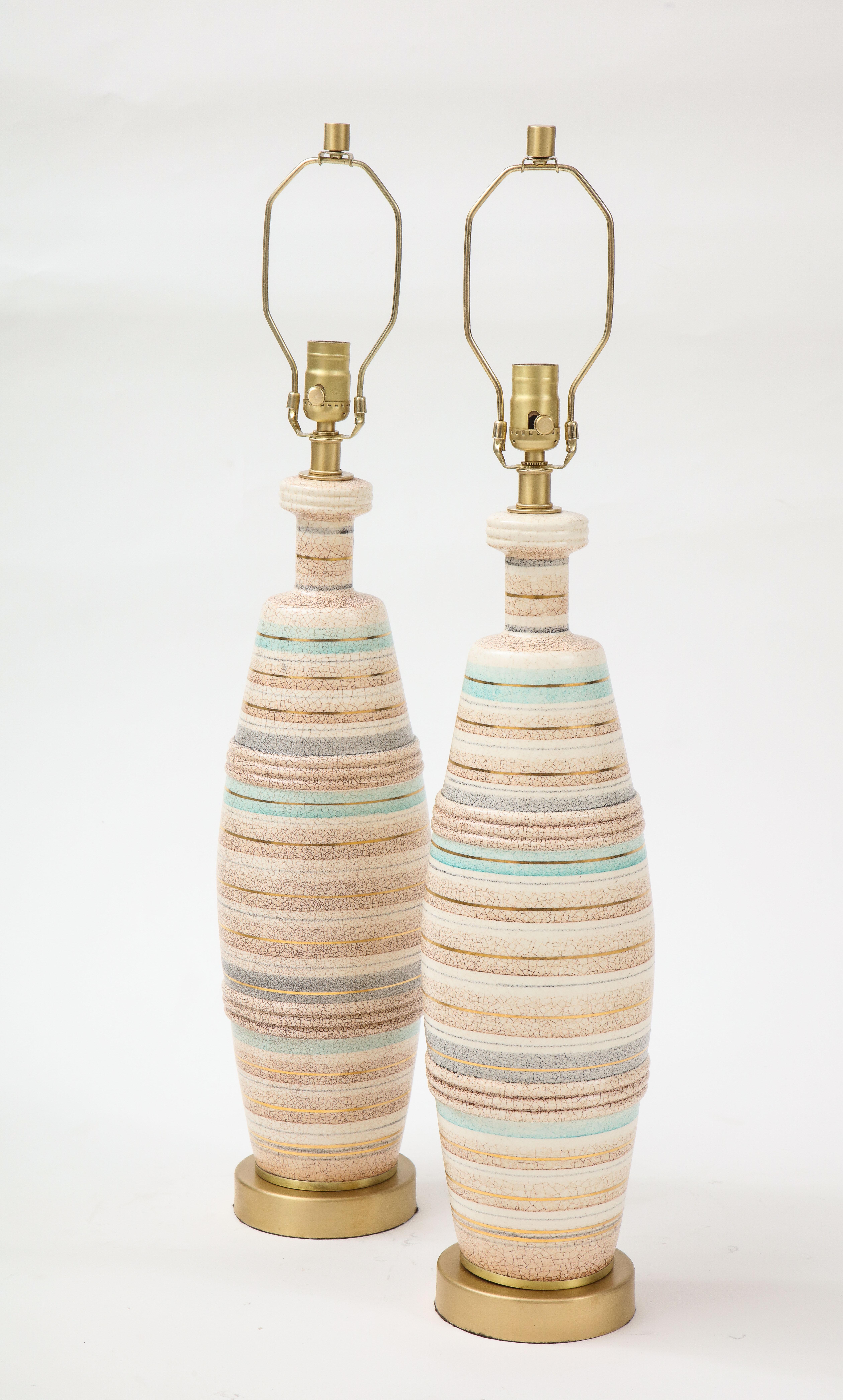 Exquisite pair of ceramic lamps featuring seaside colorful bands of tan, ivory, grey and ocean green accented with gold pinstripes, sitting on brushed brass bases. Rewired for use in USA, 100W max.