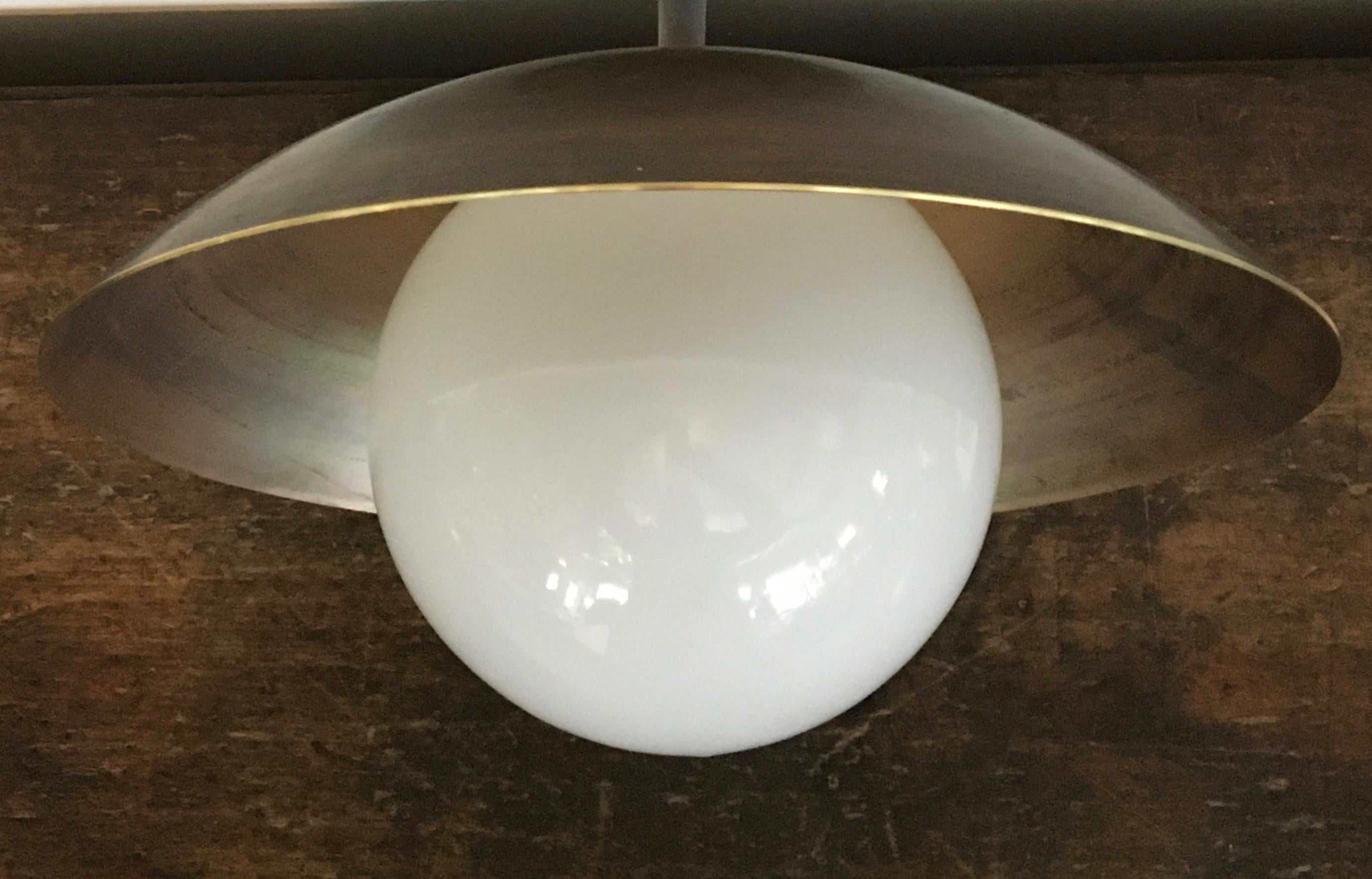 The Sasco is a versatile custom-made solid brass and glass globe light fixture, which can be mounted on the ceiling or wall. 
Shown here in our factory brass, an uneven unfinished brass patina, straight from the workshop. Also available in three