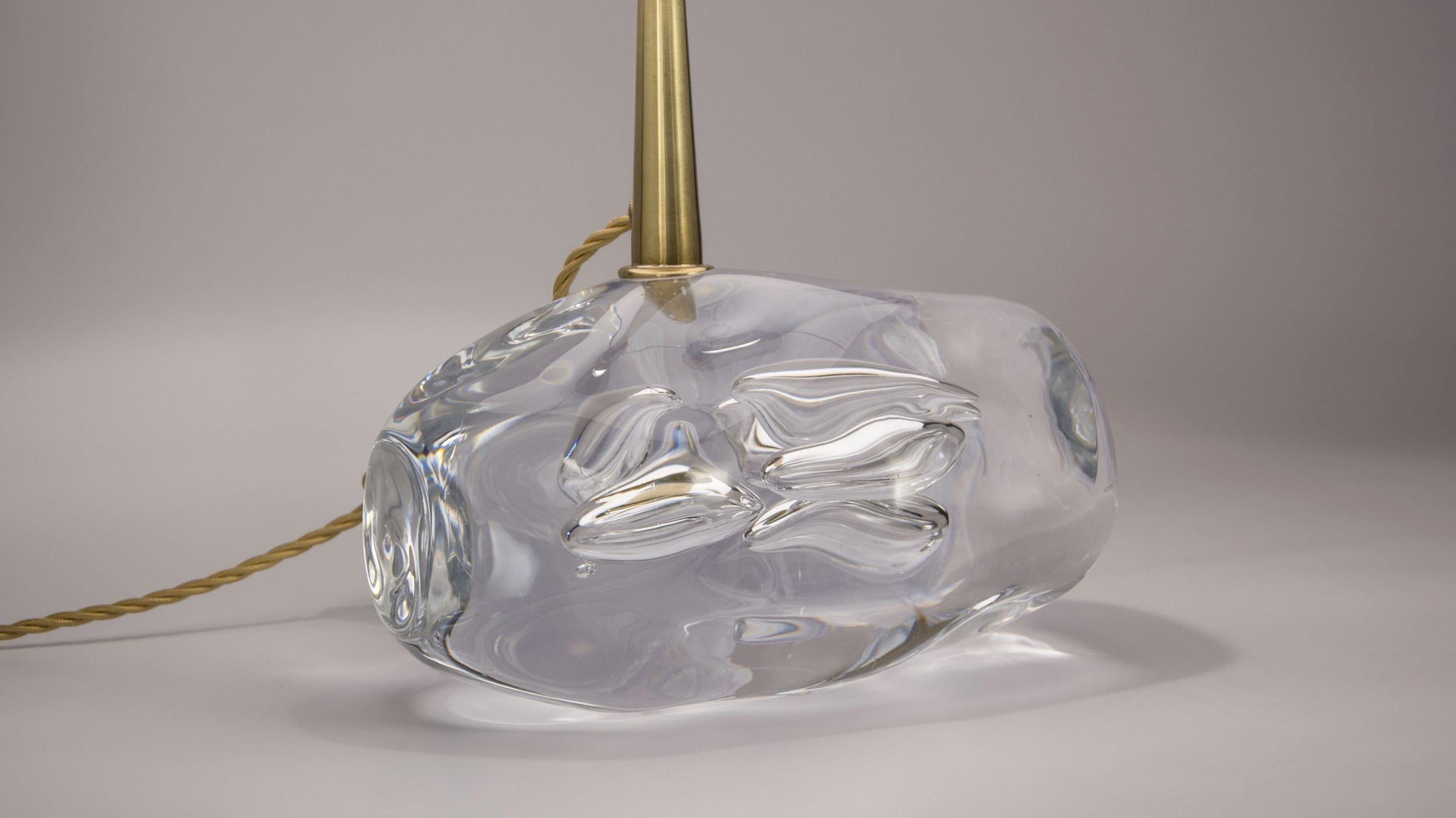 Lamp composed of a heavy base in handmade art crystal with a structure in lightly burnished brass. The shade is in ivory-tone shantung with a conical form.