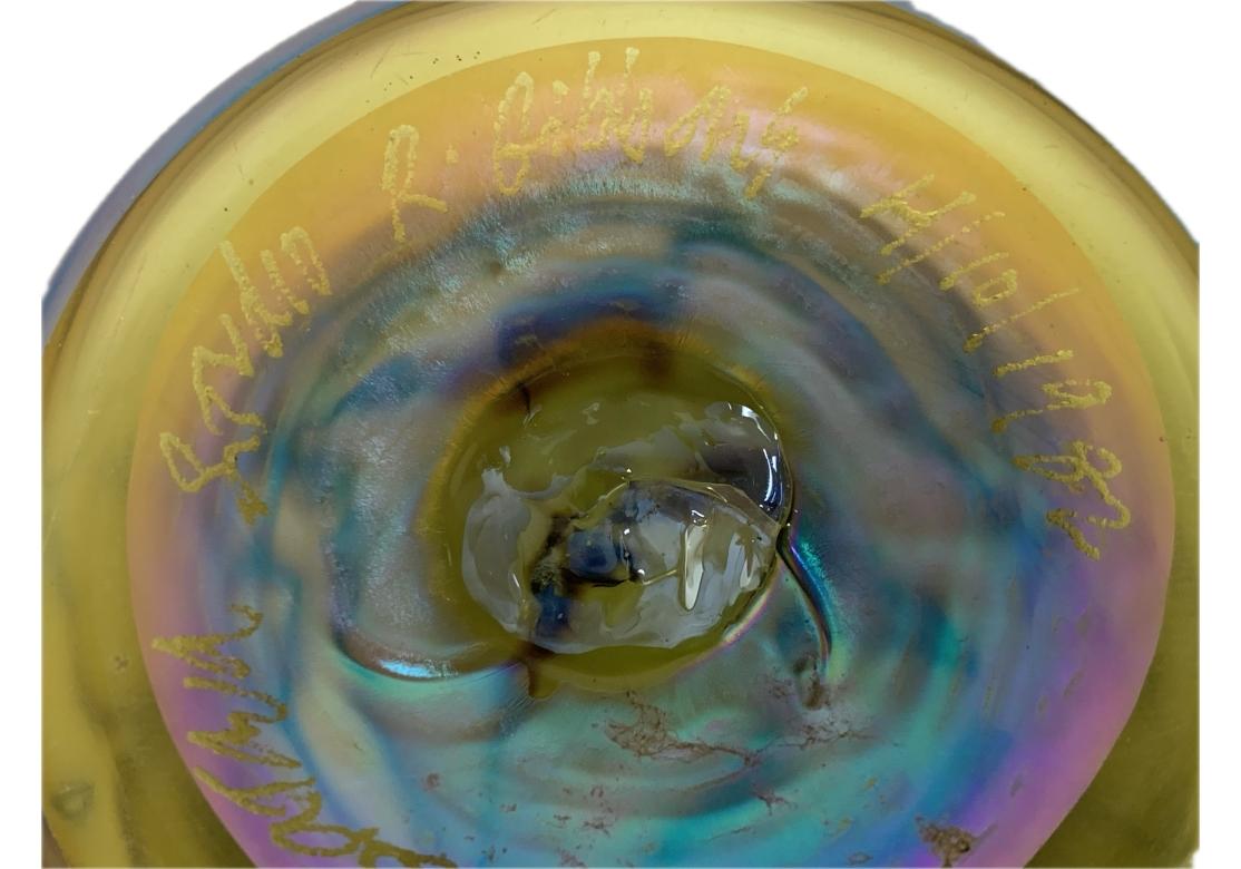 Vaso in vetro artistico con disegno di piume, colori tenui e iridescenti, con piede. Il vaso è firmato Studio A, Gibbons e datato 1982.
Dimensioni: 4 1/2