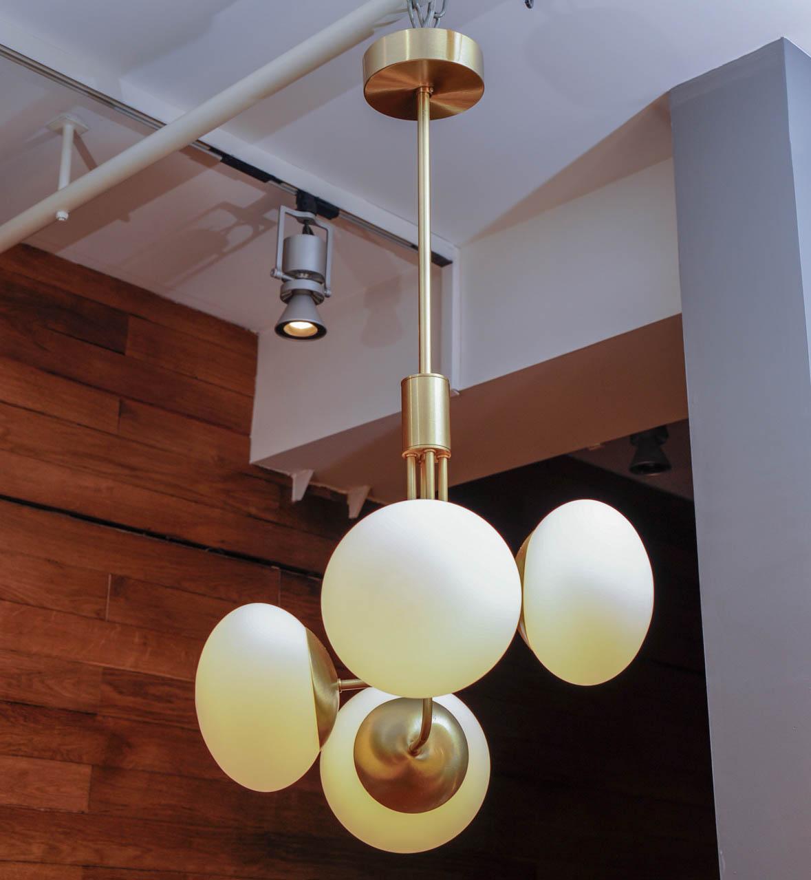 Nice and elegant suspension made of satin brass, four arms of light with white glass globes.
 