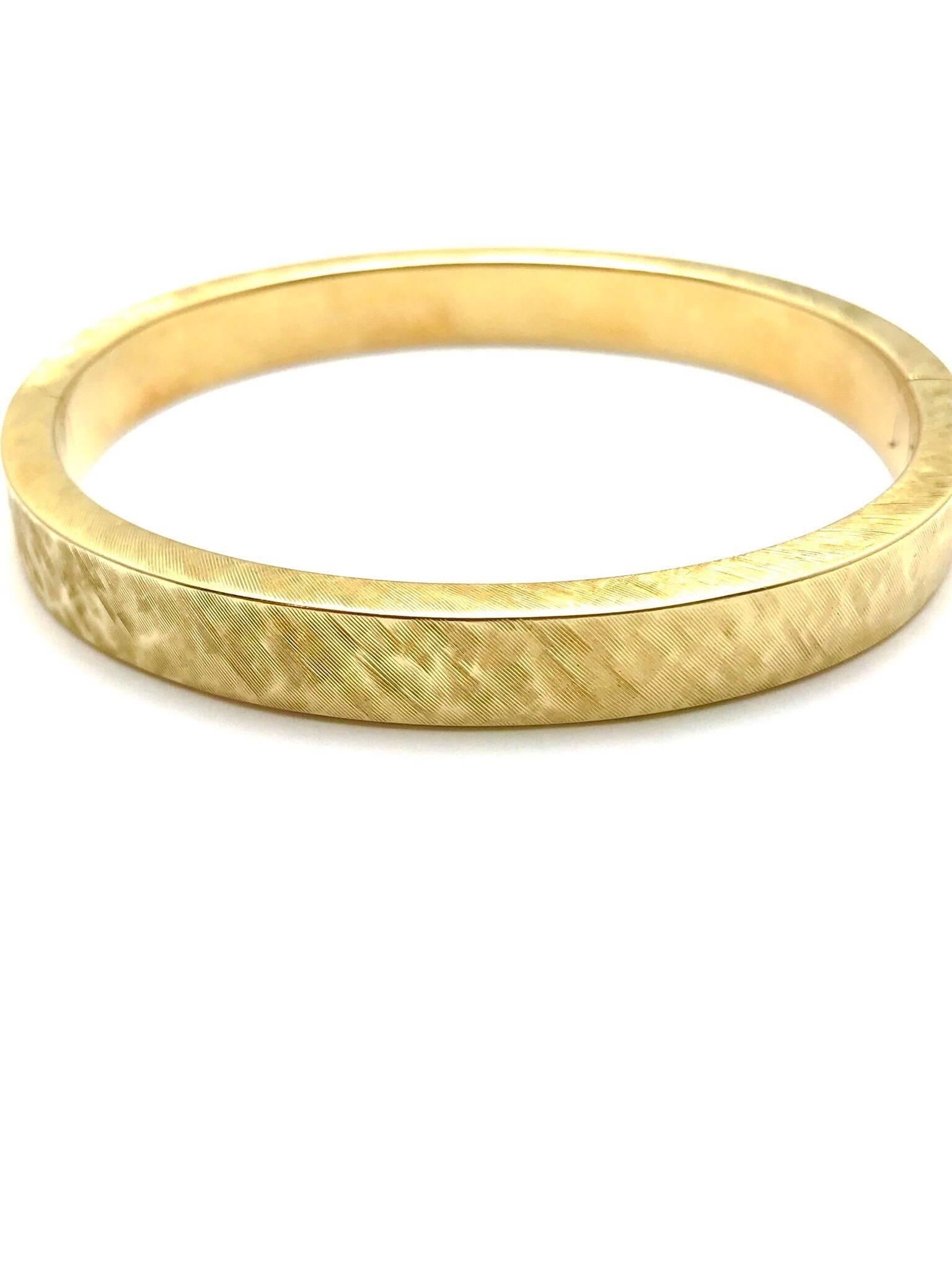 This is a beautiful and easy to wear satin finished 14 Karat yellow gold bangle bracelet with a hidden clasp.  The bangle is designed in an oval shape to better fit the wrist, and the hidden clasp and hinge gives it a continuous look.  A great piece