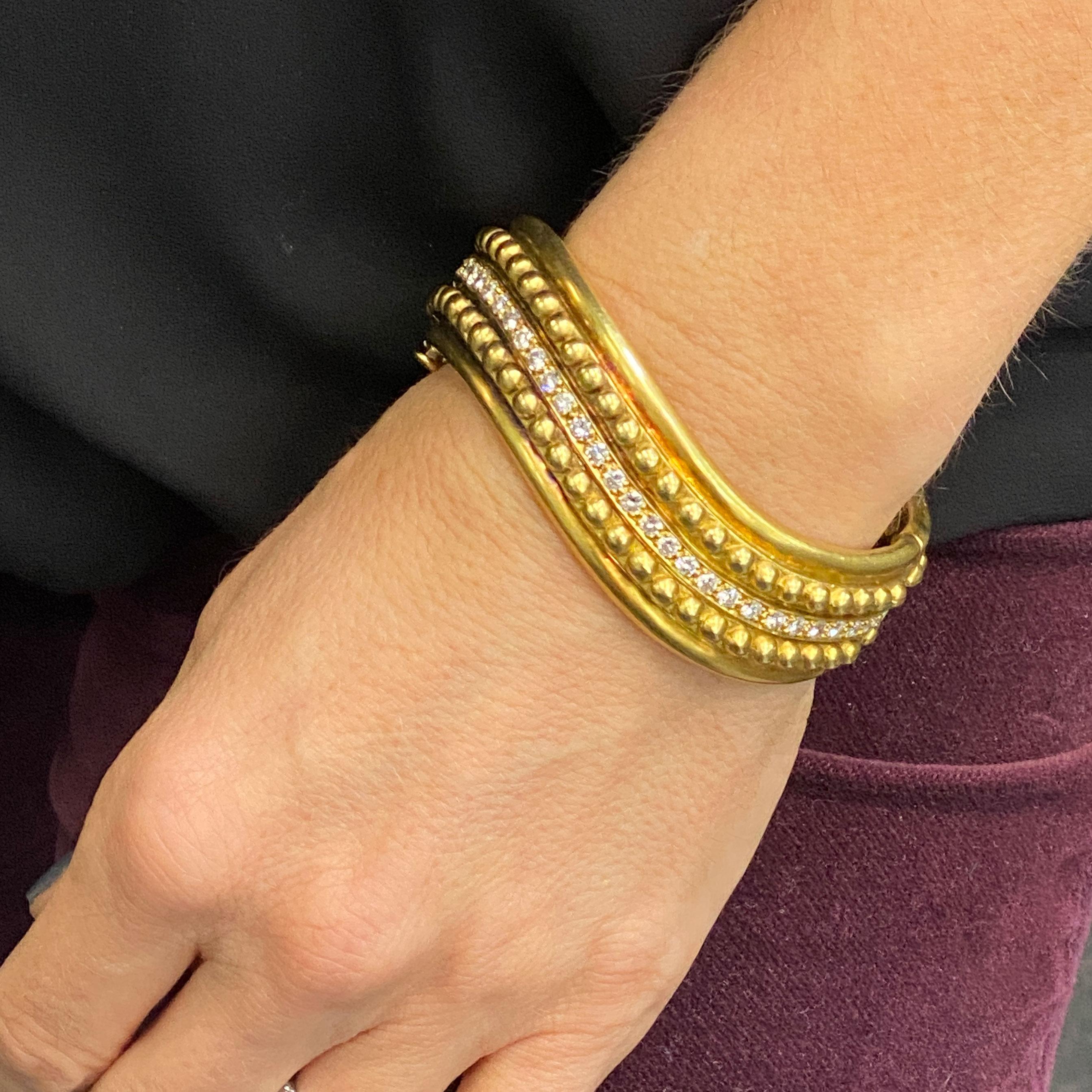 Exquisite satin finished 18 karat yellow gold hinged bangle featuring 30 round brilliant cut white diamonds (2.40 CTW) graded F-G color and VS clarity. The solid textured bangle measures .75 inches in width and approximately 7 inches in