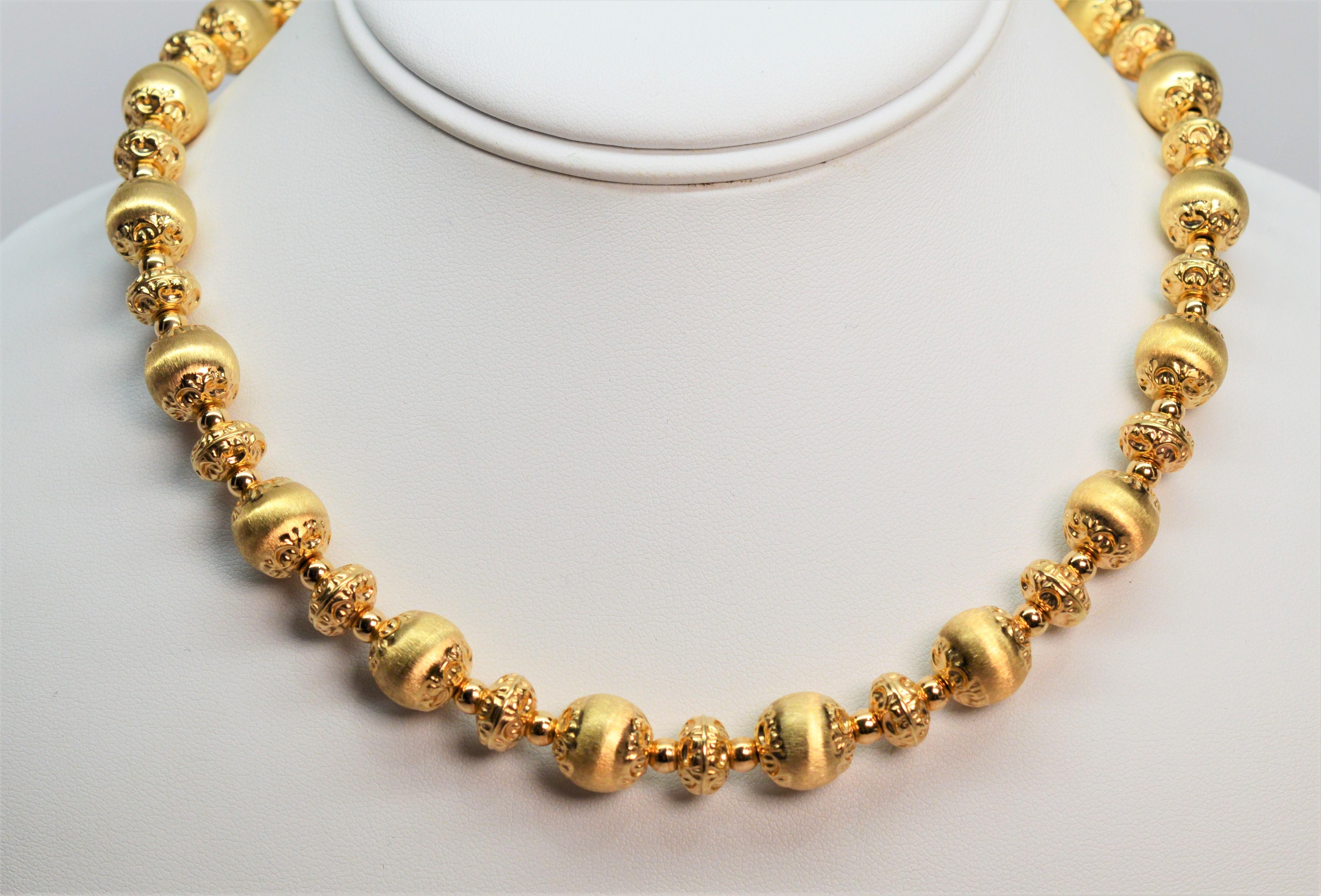 The brilliant mix of fine satin gold and highly polished ornately crafted gold beads and findings create this exquisite Italian made fourteen karat  14k yellow gold necklace. 
The alternating 10mm and 8mm beading with complementary textures creates