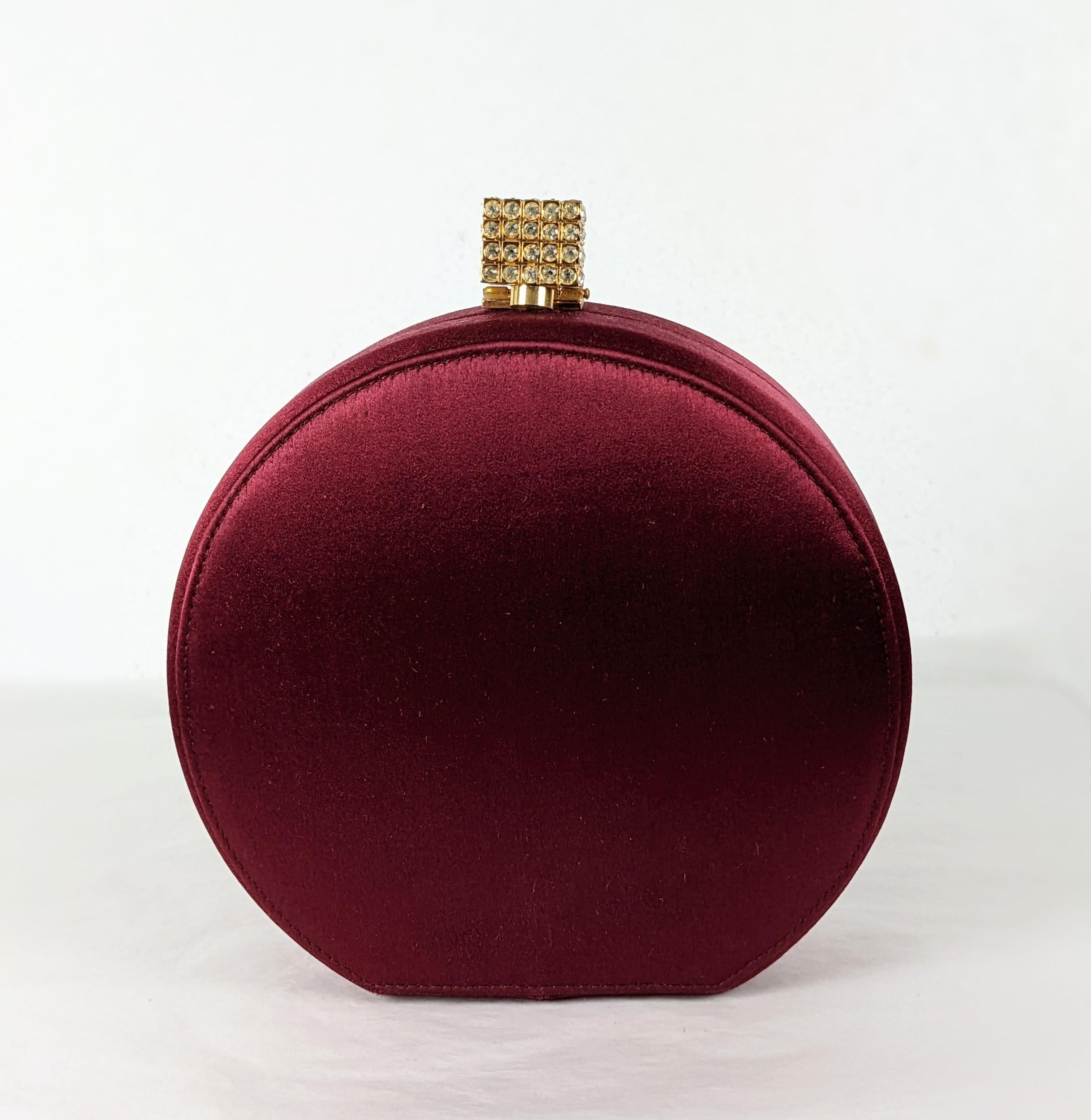 Satin Minaudiere in wine silk retailed by Bergdorf Goodman. Round form with long strap. Pave cube clasp. 6