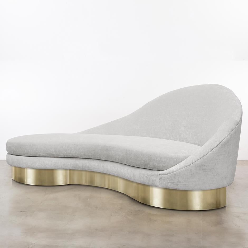 The satine sofa inspired by the curvature of Gaudi architecture features an asymmetrical sophisticated velvet slope that meets a fractured gold leaf plinth base to make a minimal and elegant statement. Fully custom and made to order in California.