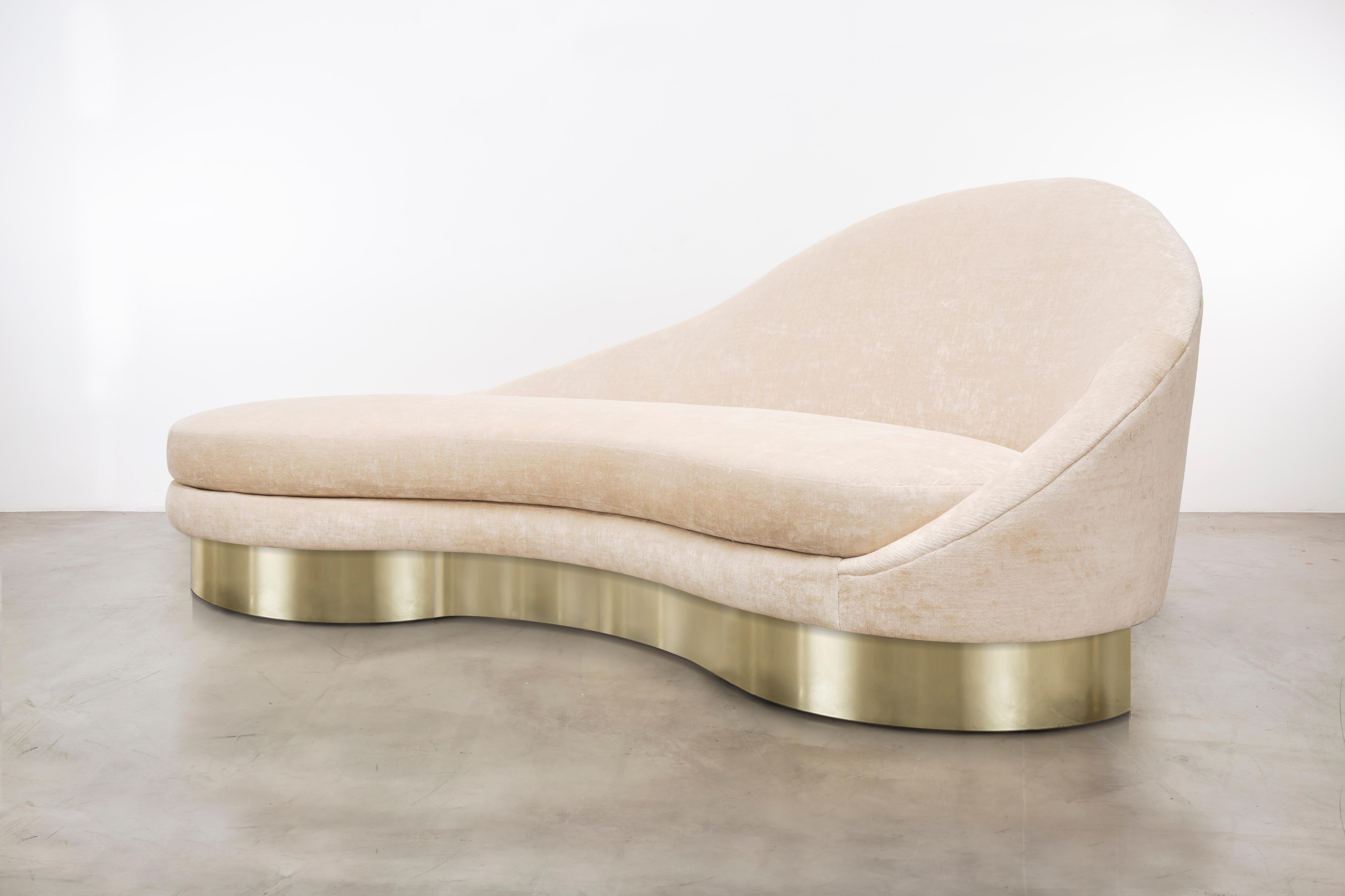 The Satine sofa inspired by the curvature of Gaudi architecture features an asymmetrical sophisticated velvet slope that meets a metal plinth base to make a minimal and elegant statement. Fully custom and made to order in California. As shown in