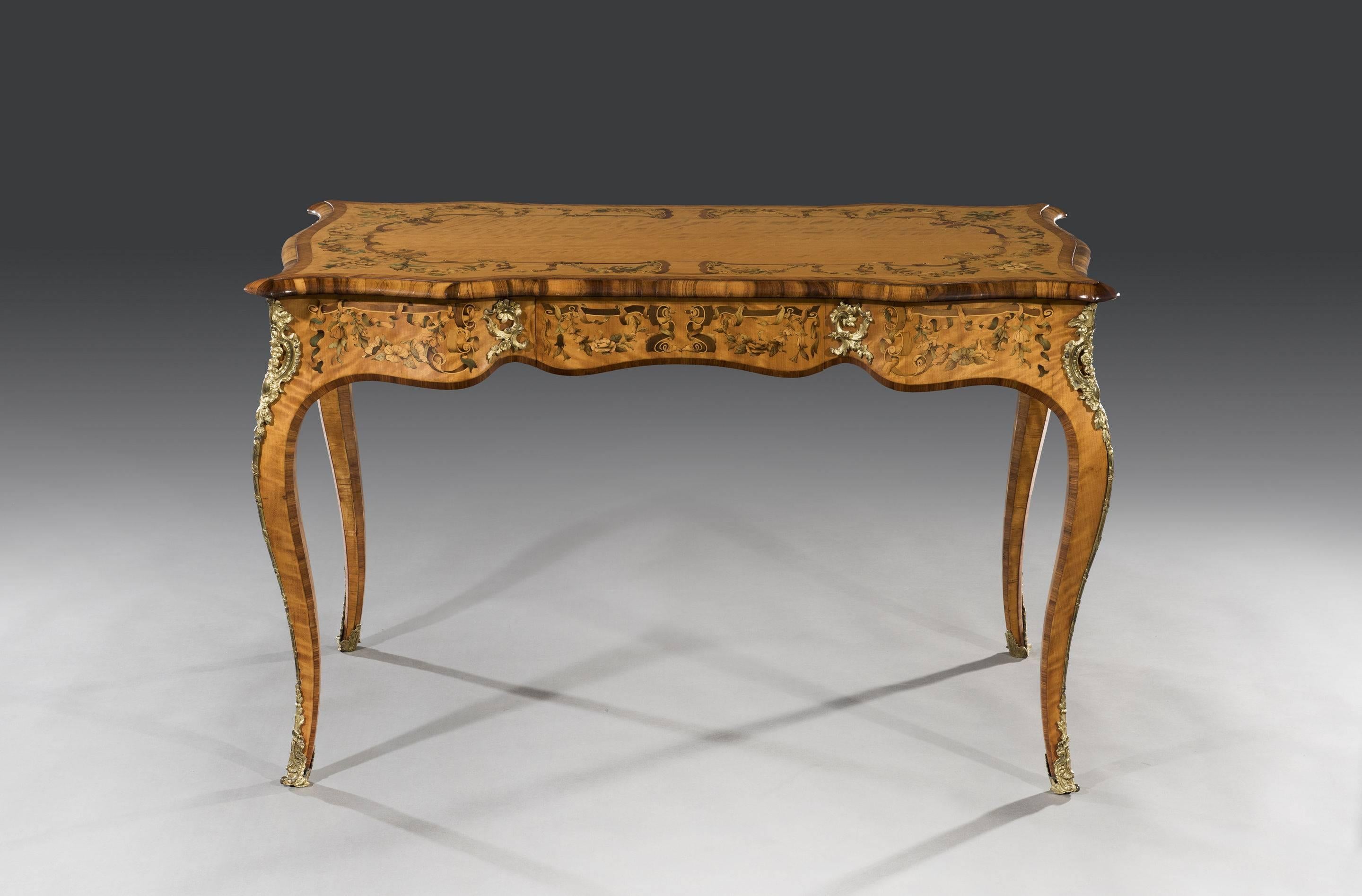 The book-matched veneered satinwood top with serpentine sides and canted corners is adorned with stained floral marquetry designs with kingwood crossbanding and gonçalo alves mouldings. The gilt bronze mounts fitted to the marquetry decorated